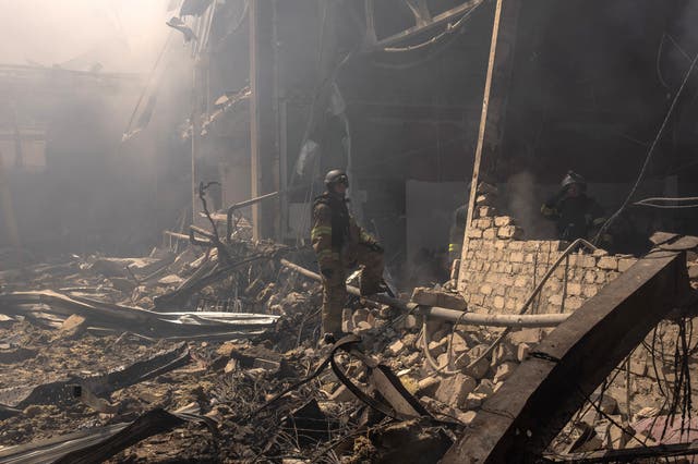 <p>Ukrainian emergency and rescue workers stand in the debris at a destroyed supermarket in August</p>