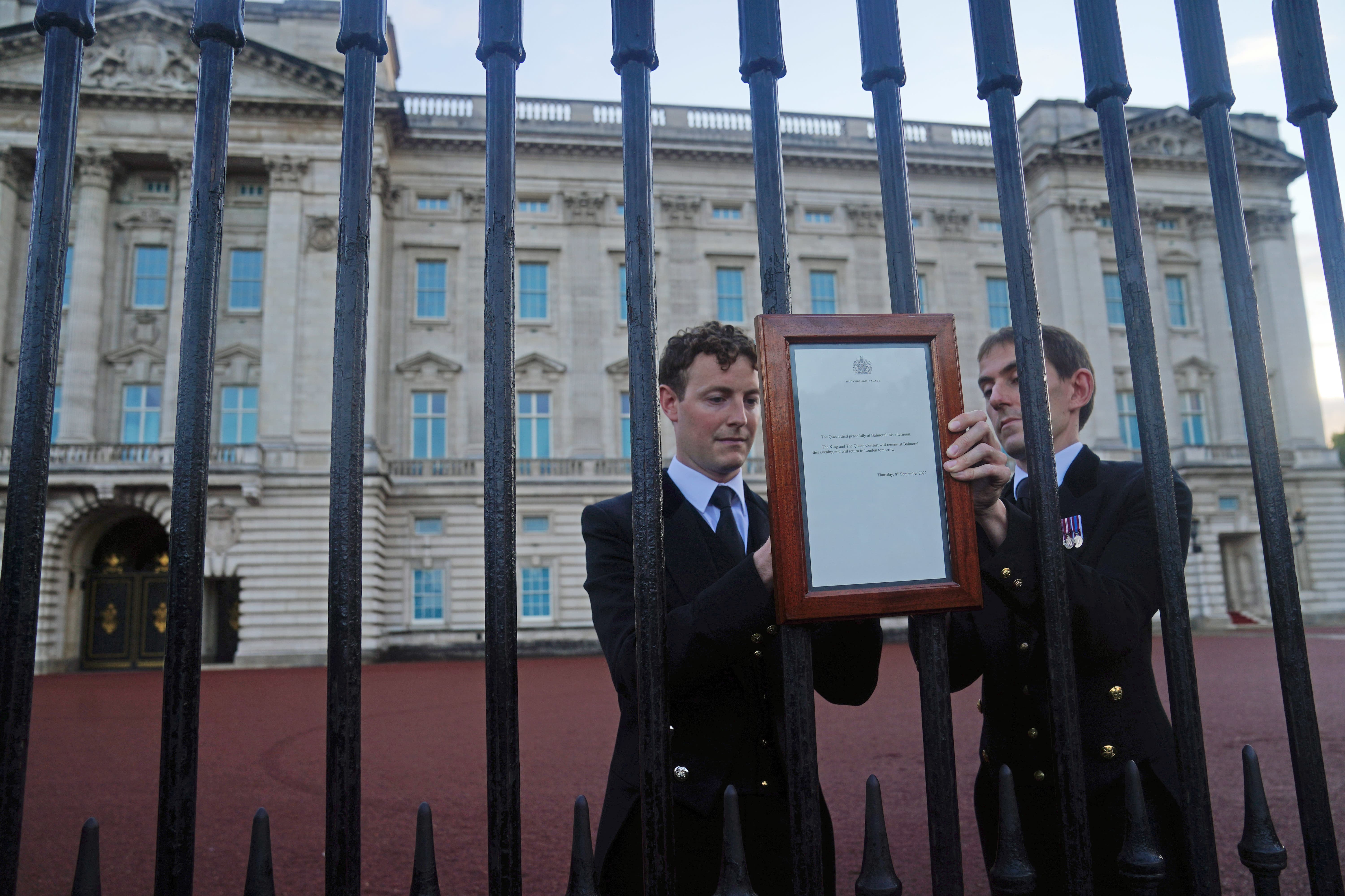 Members of royal household staff post a notice on the gates of the Buckingham Palace in London announcing the death of Queen Elizabeth II (Victoria Jones/PA)