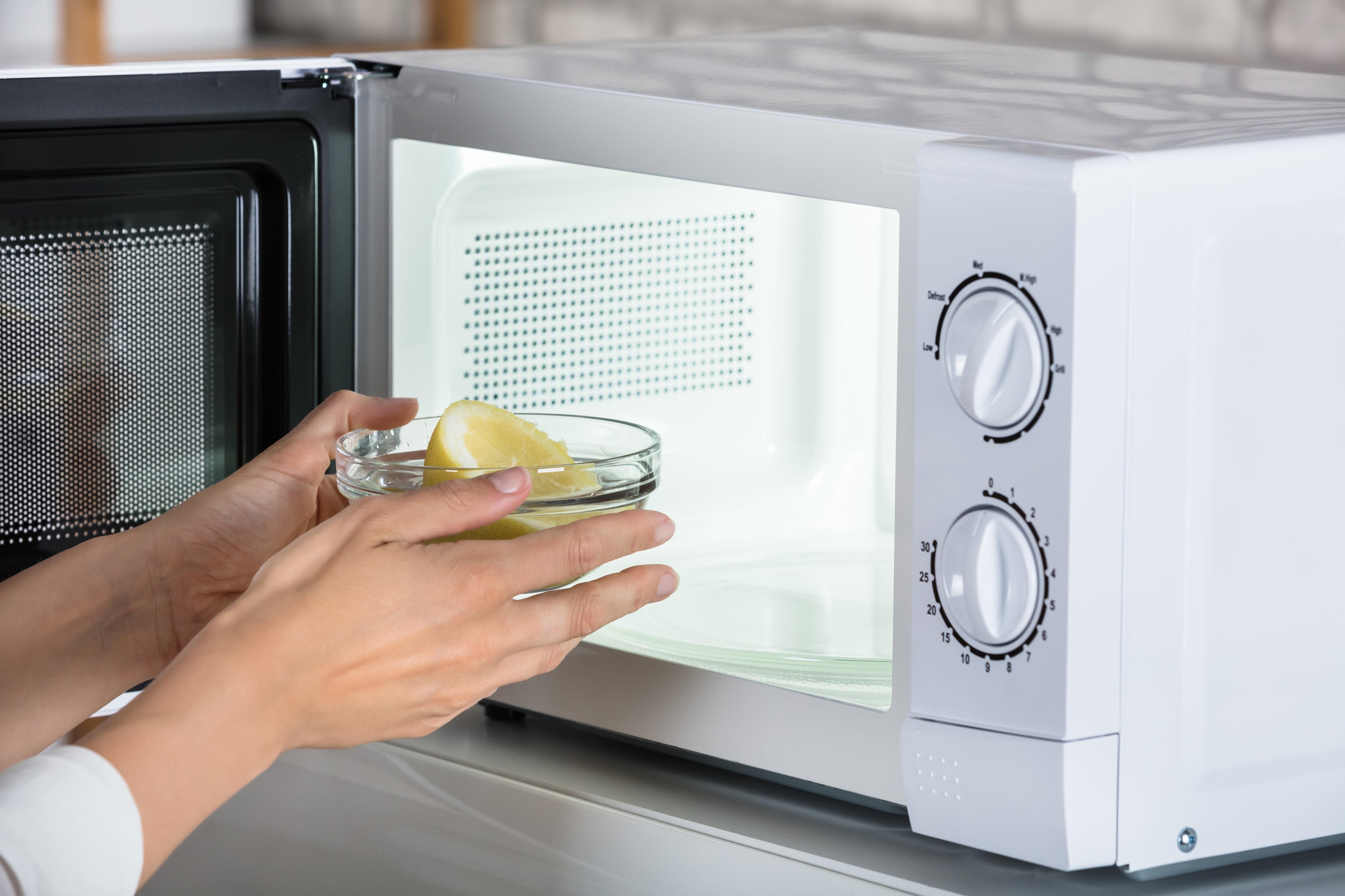 Woman placing a bowl of lemon slices in the microwave