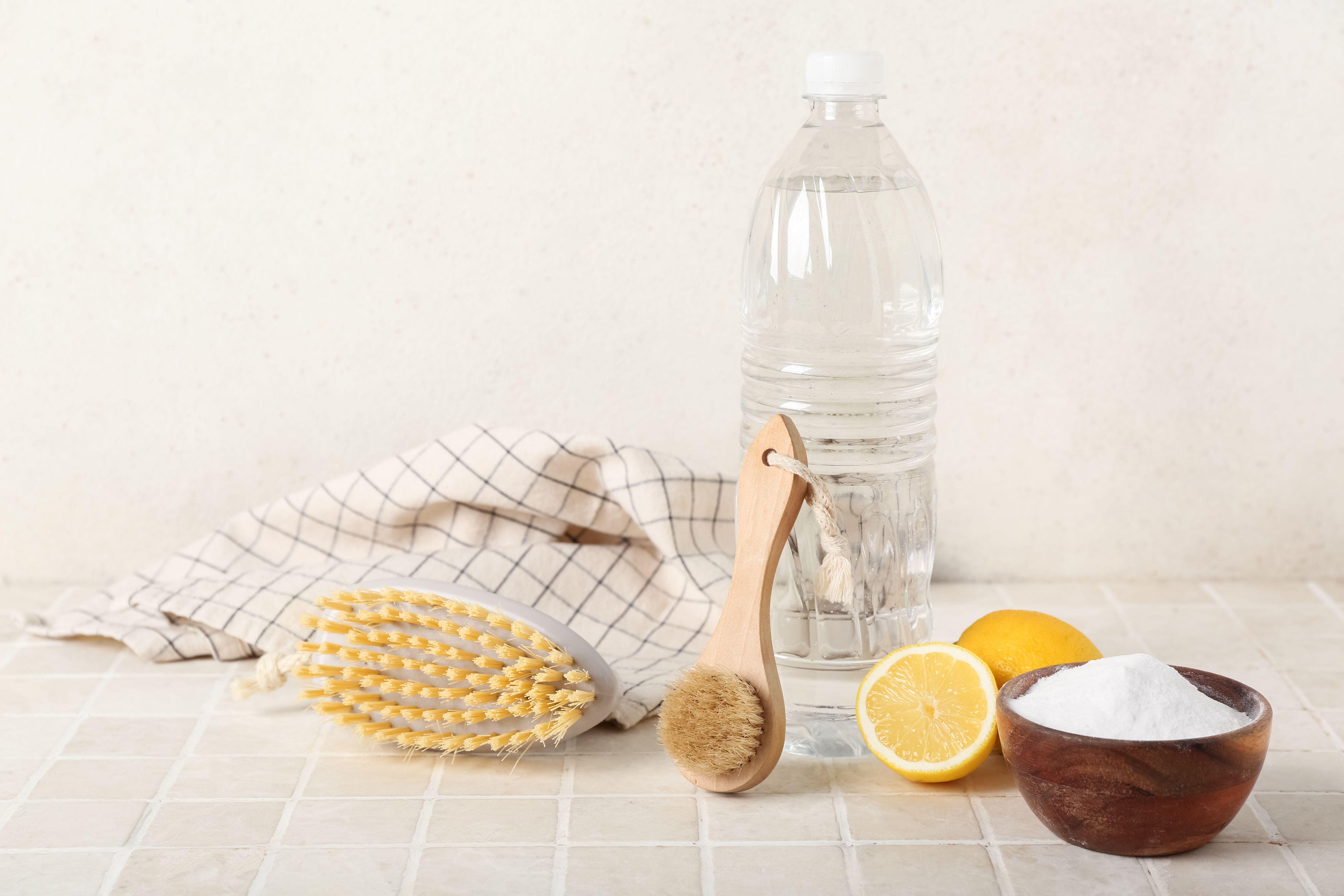 Bowl of baking soda, vinegar, cleaning brushes and lemons on table