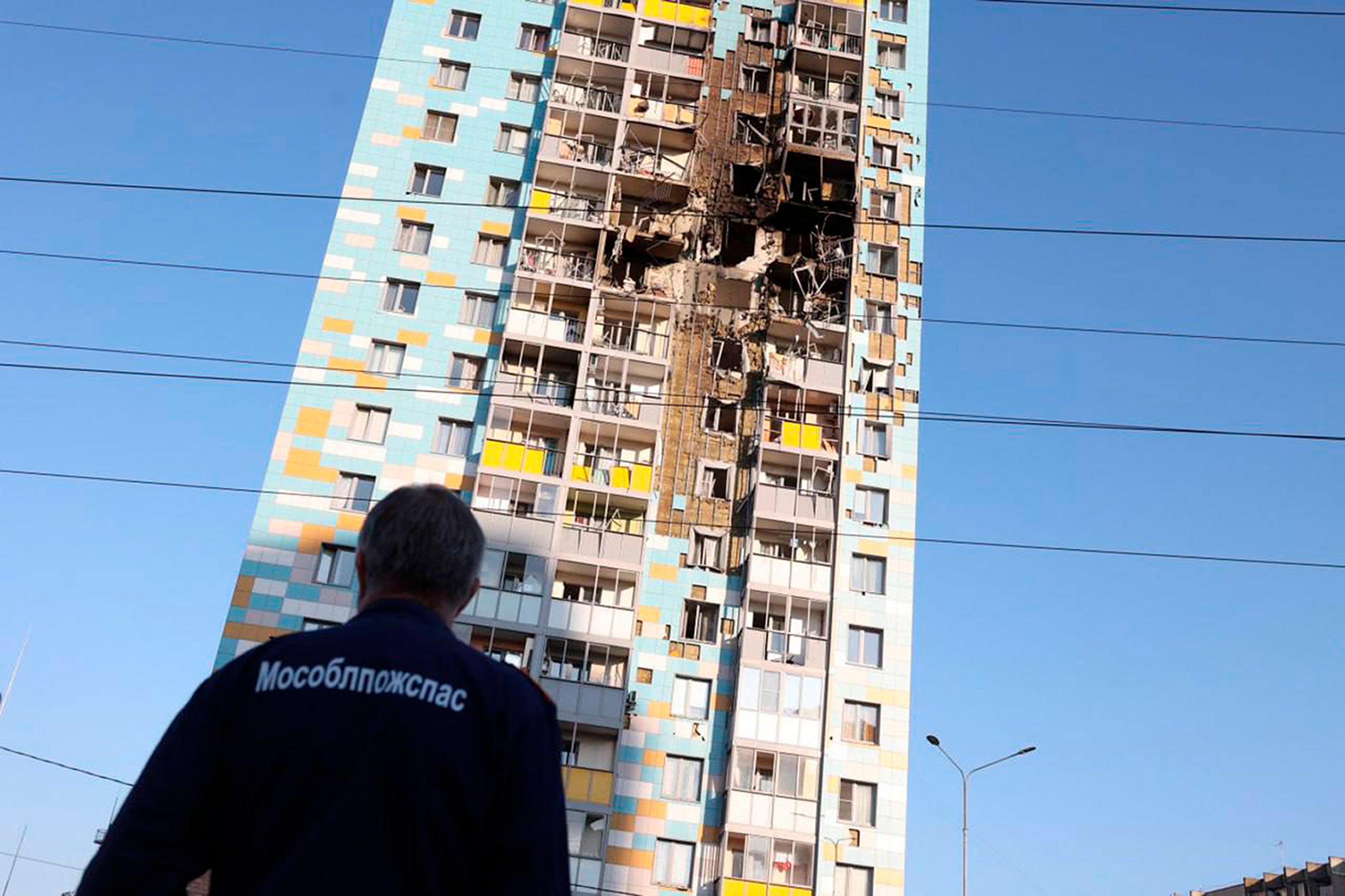 A man looks at the multi-storey residential building hit in an alleged Ukrainian drone attack in Ramenskoye