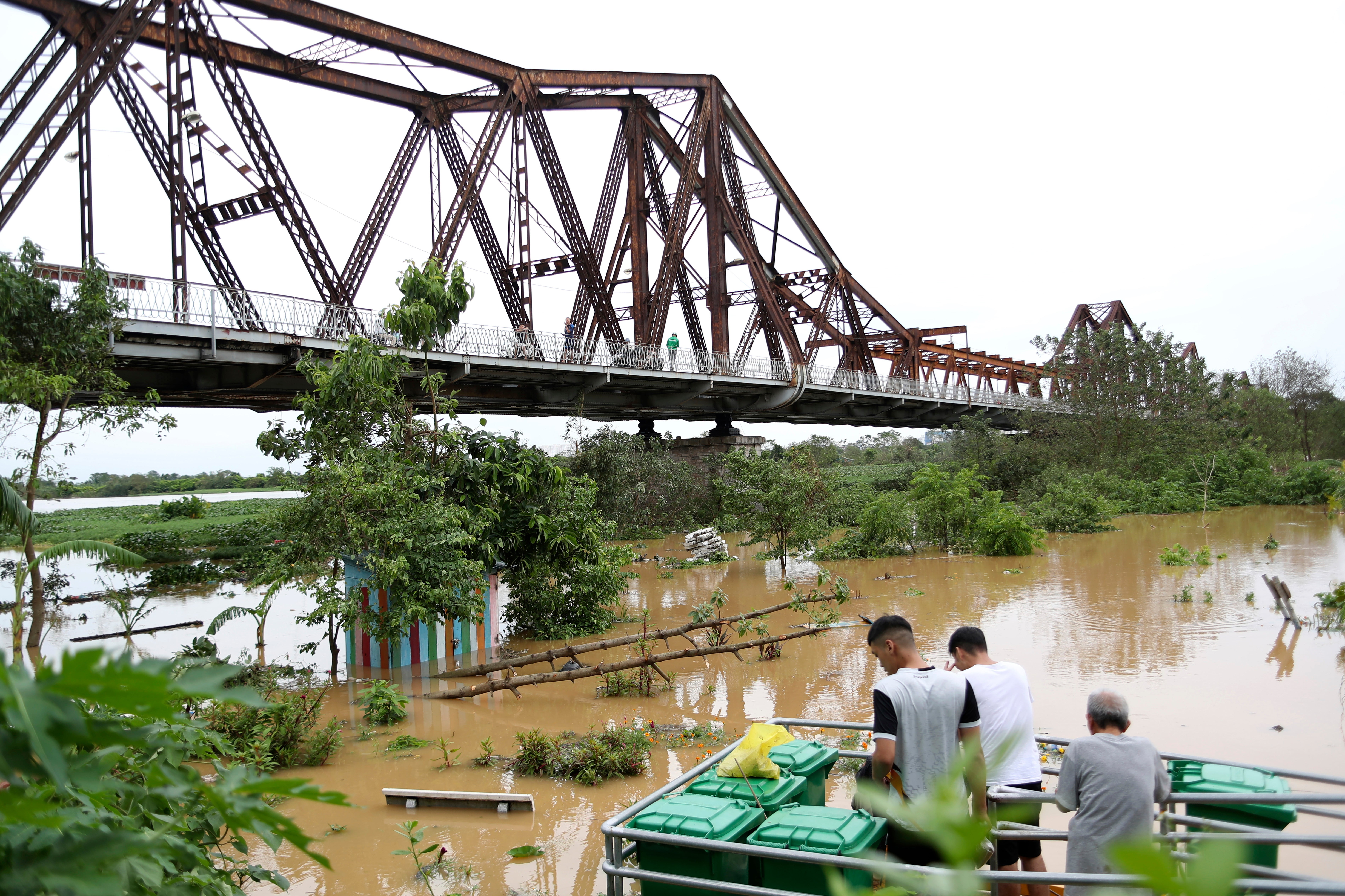 People watch the flooded Red river next to iconic Long Bien bridge, following Typhoon Yagi in Hanoi, Vietnam