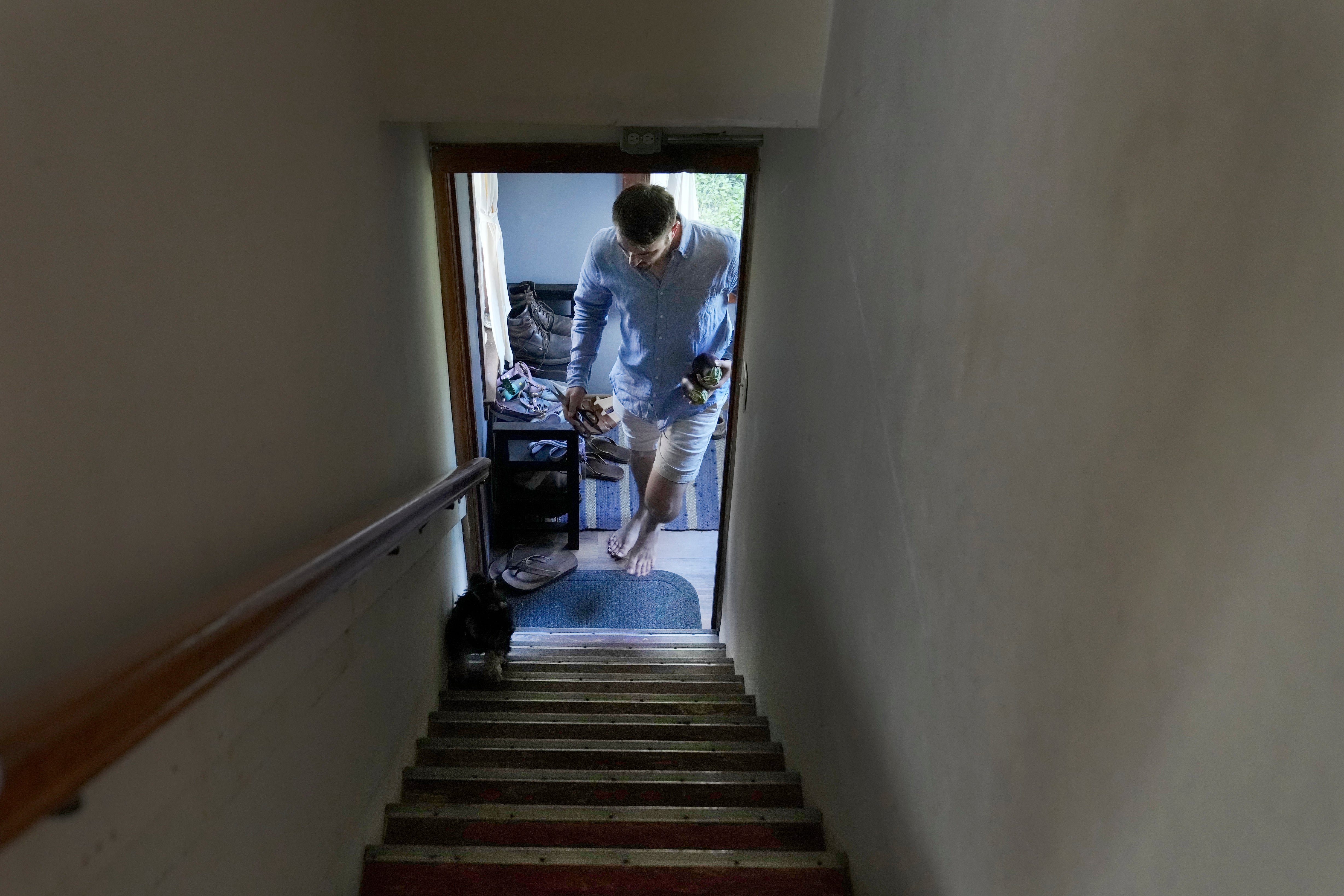 Steven Manetta, a cancer patient, returns from the garden with an eggplant for dinner as his dog Basil leads him up the stairs at his home in Lemont, Ill., Thursday, Aug. 29, 2024