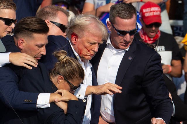 <p>US Republican candidate Donald Trump is seen with blood on his face surrounded by secret service agents as he is taken off the stage at a campaign event in Butler, Pennsylvania, on July 13, 2024</p>