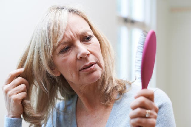 <p>Mature woman looking at her hair brush concerned about hair loss</p>
