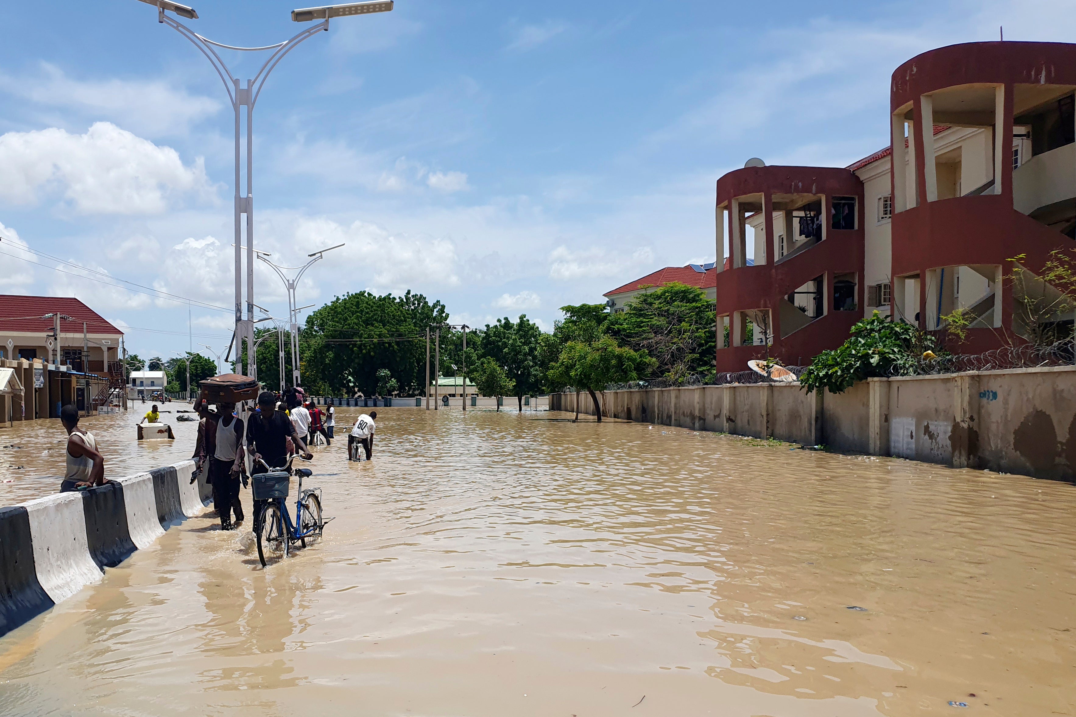 People walk through floodwaters following a dam collapse in Maiduguri, Nigeria