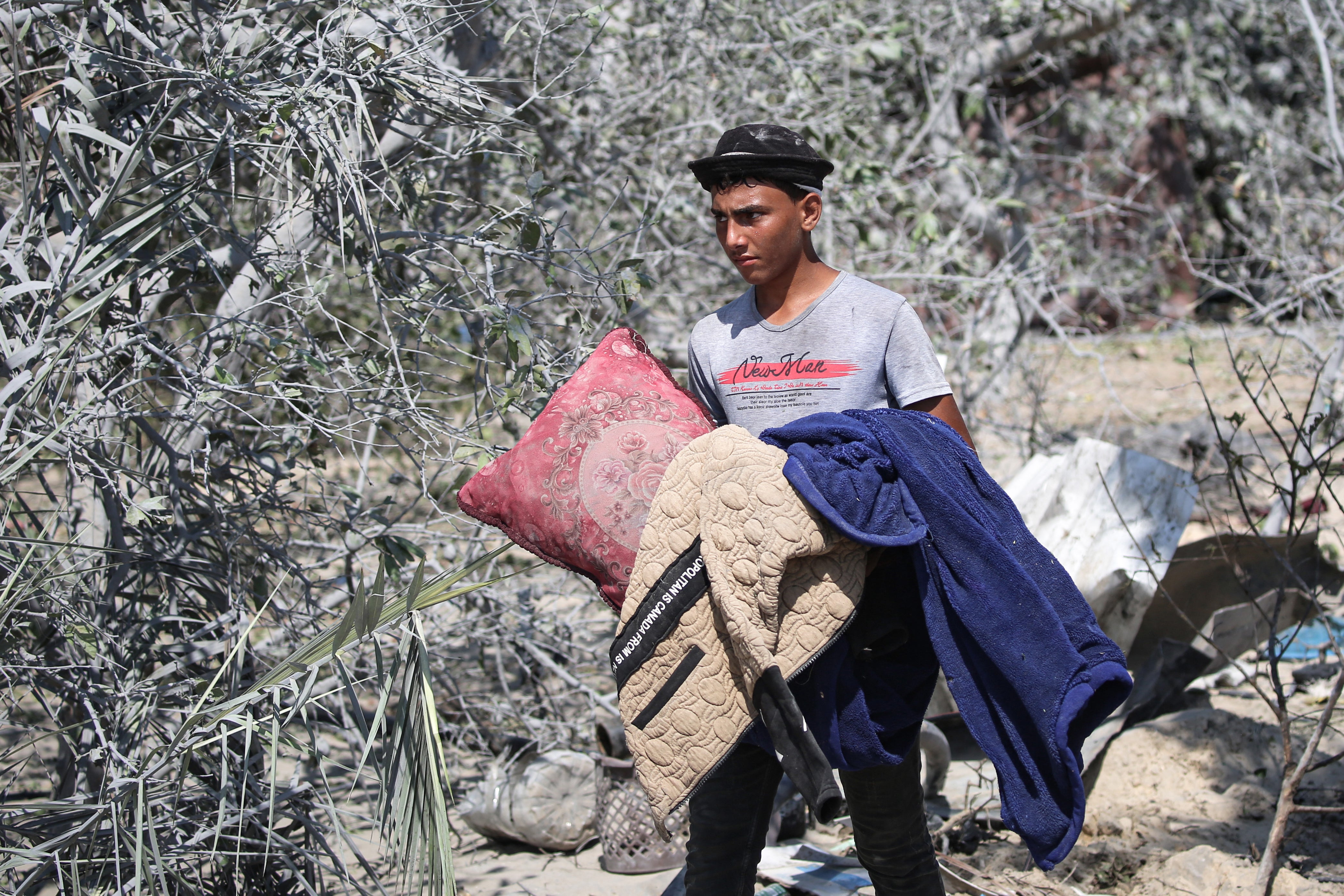 A Palestinian man collects belongings at the site of Israeli strikes on the al-Muwasi displacement camp in Khan Younis