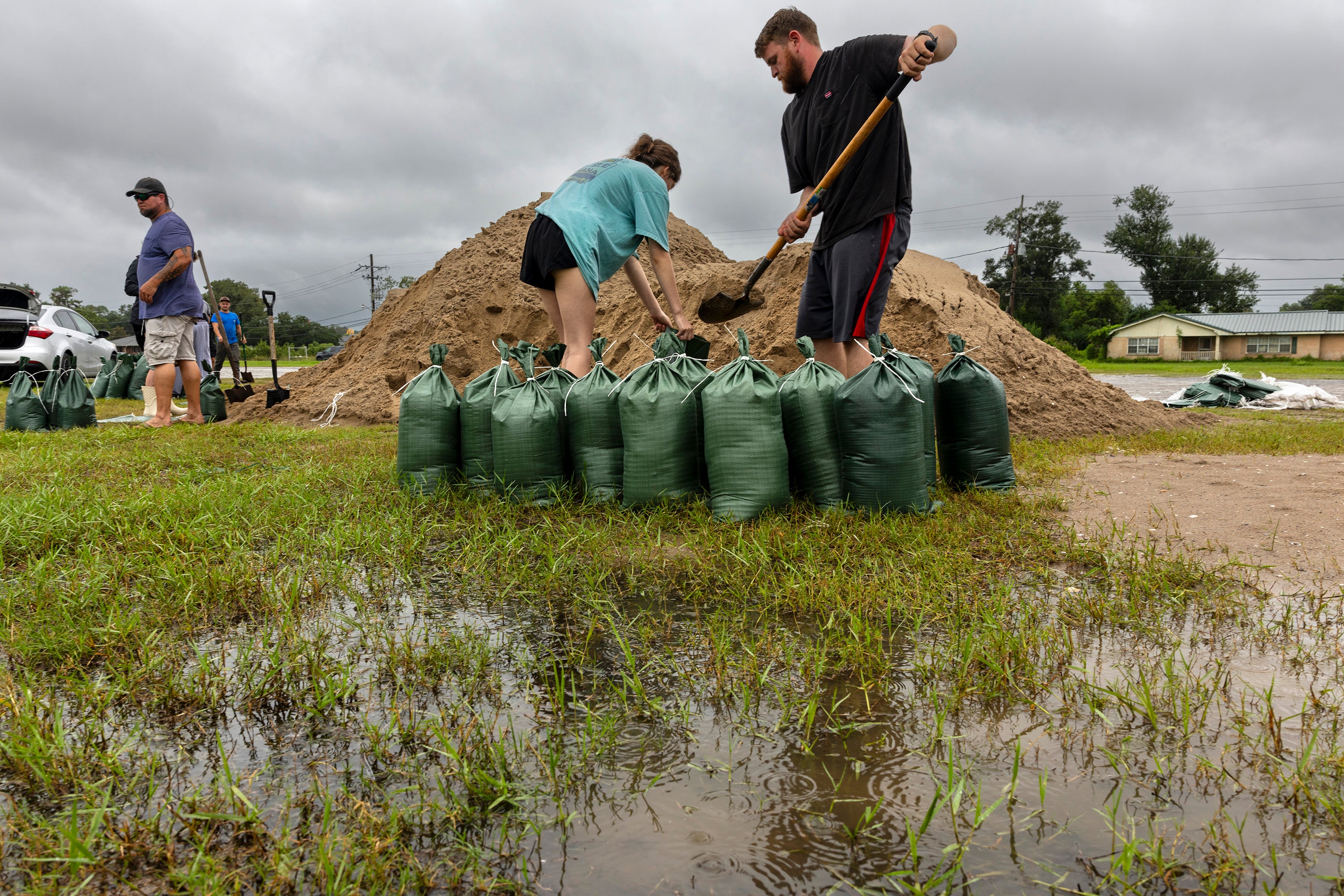 Nolan and Macie Melancon fill up sandbags for their home on Tuesday, as rain falls. Residents of New Orleans lined up for sandbags at a YMCA parking lot, and teenagers in Lafitte worked to fill them for hours.