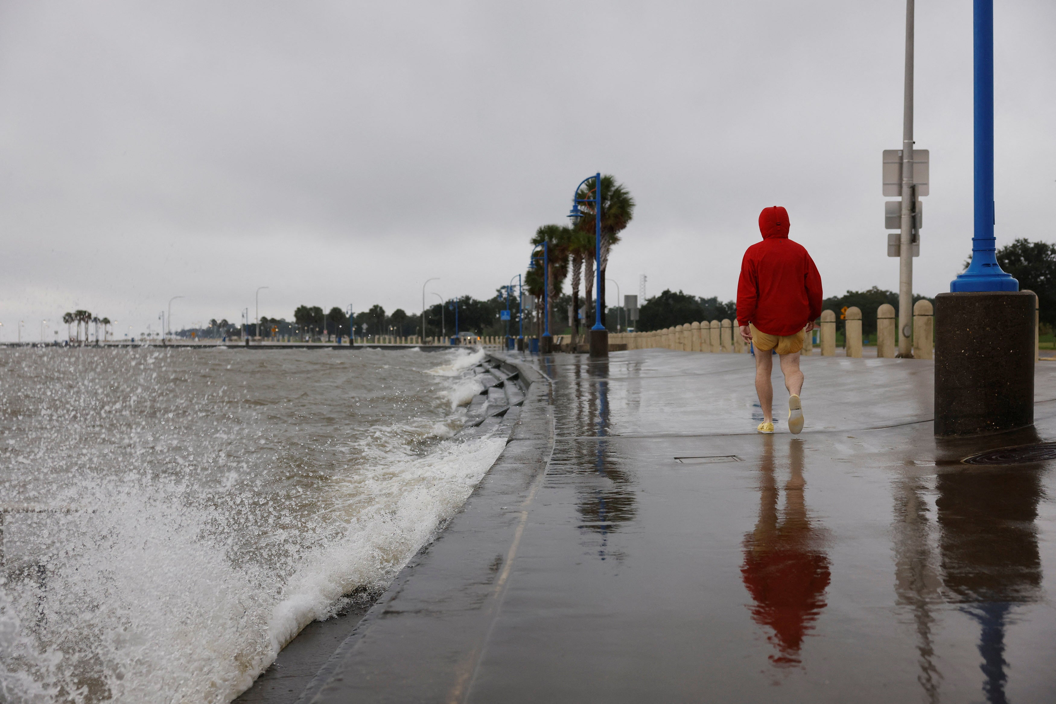 A person in a raincoat walks by the waves from Lake Pontchartrain as they crash against the seawall in New Orleans on Wednesday. Hurricane Francine is expected to make landfall shortly.