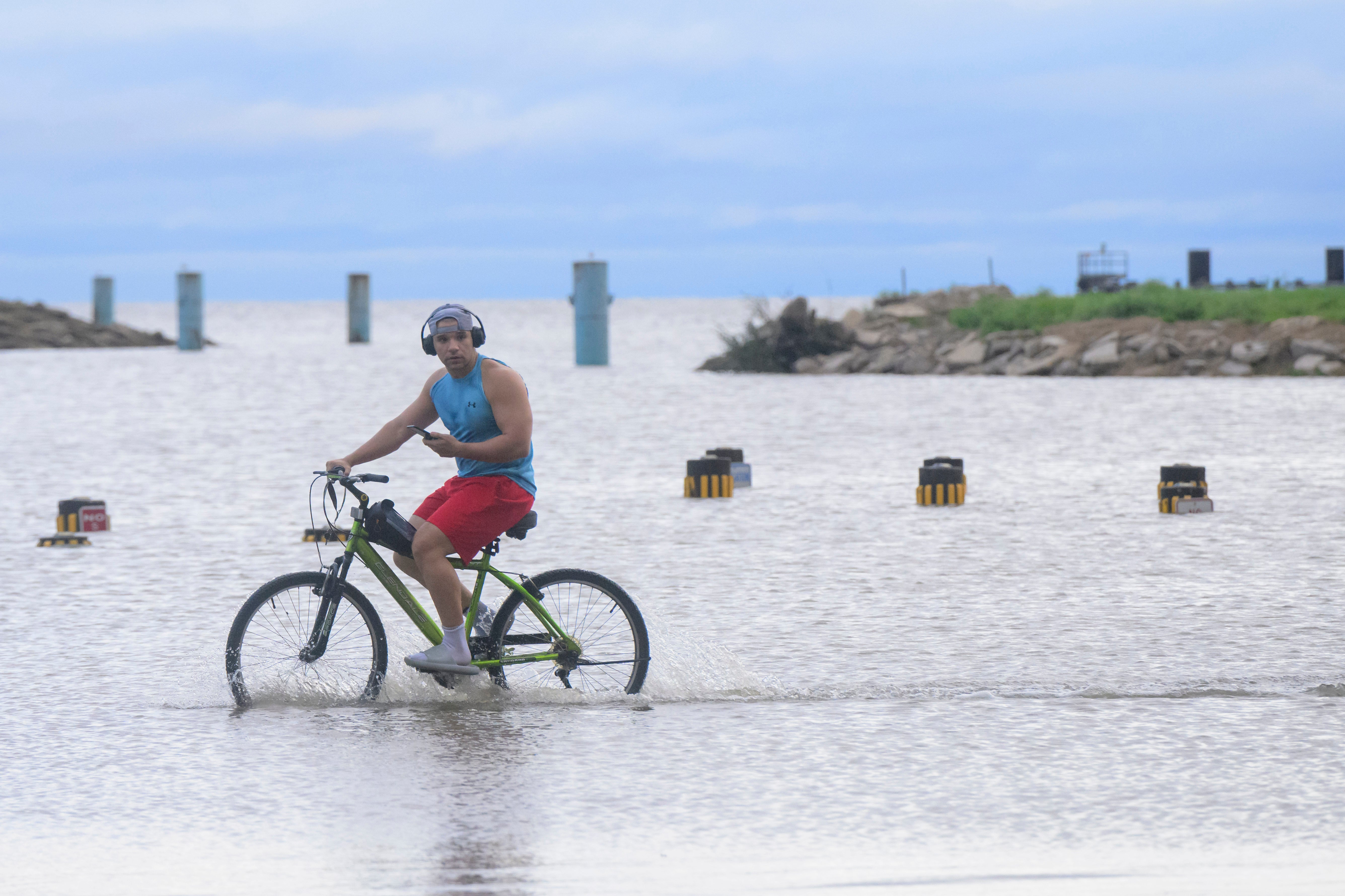 A man bikes through floodwaters from Hurricane Francine in Jefferson Parish on Thursday. Pumps in the parish reportedly could not keep up from the storm’s onslaught. Water levels are receding, but streets remain flooded.