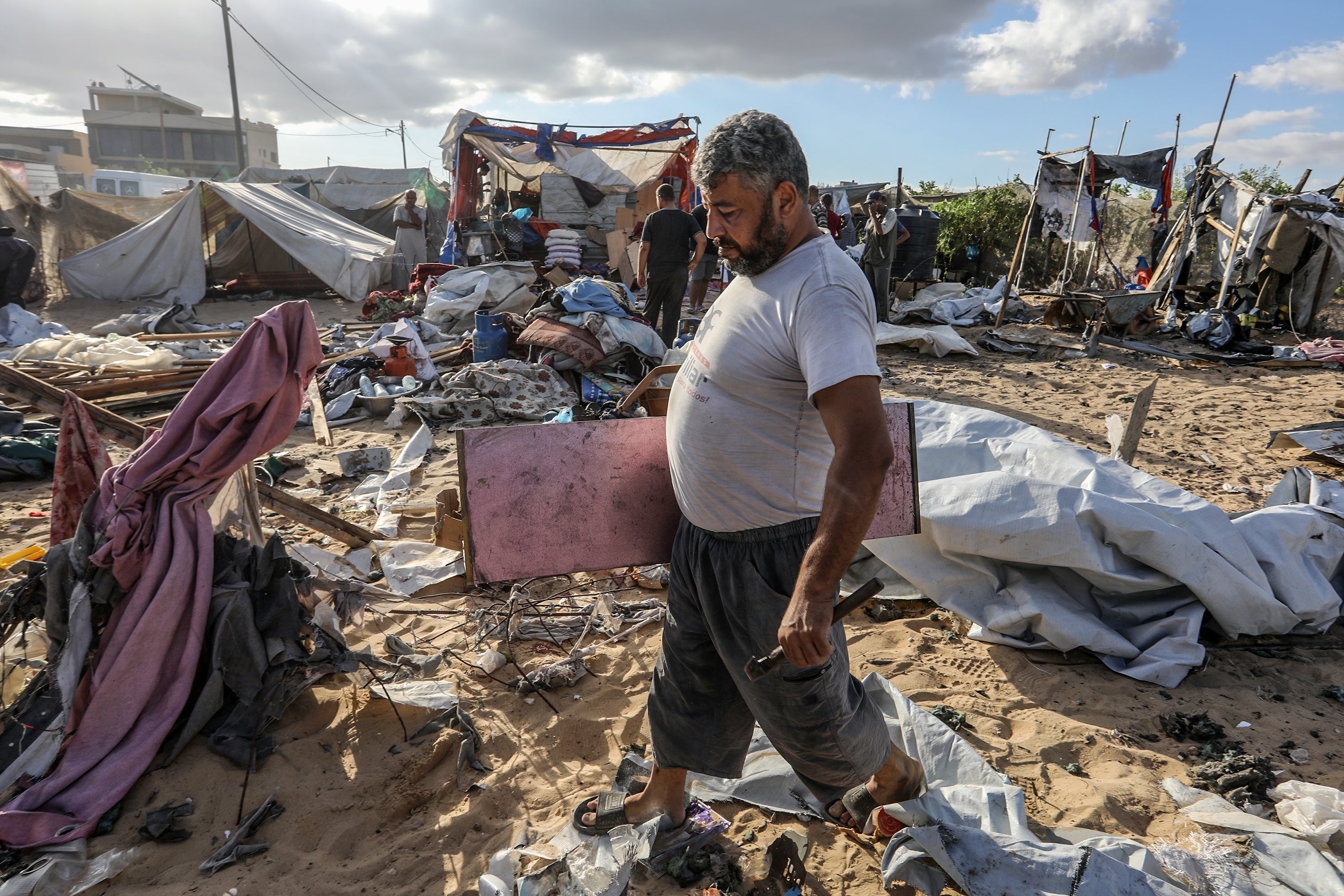 Palestinians search their belongings among destruction following an airstrike on Palestinian tents in al-Mawasi area, Khan Yunis