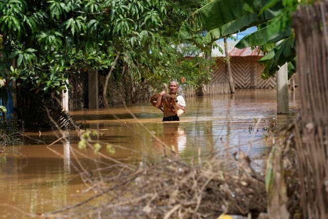 <p>A man carries a dog through a flooded road in Naypyitaw, Myanmar, amid deadly flooding </p>