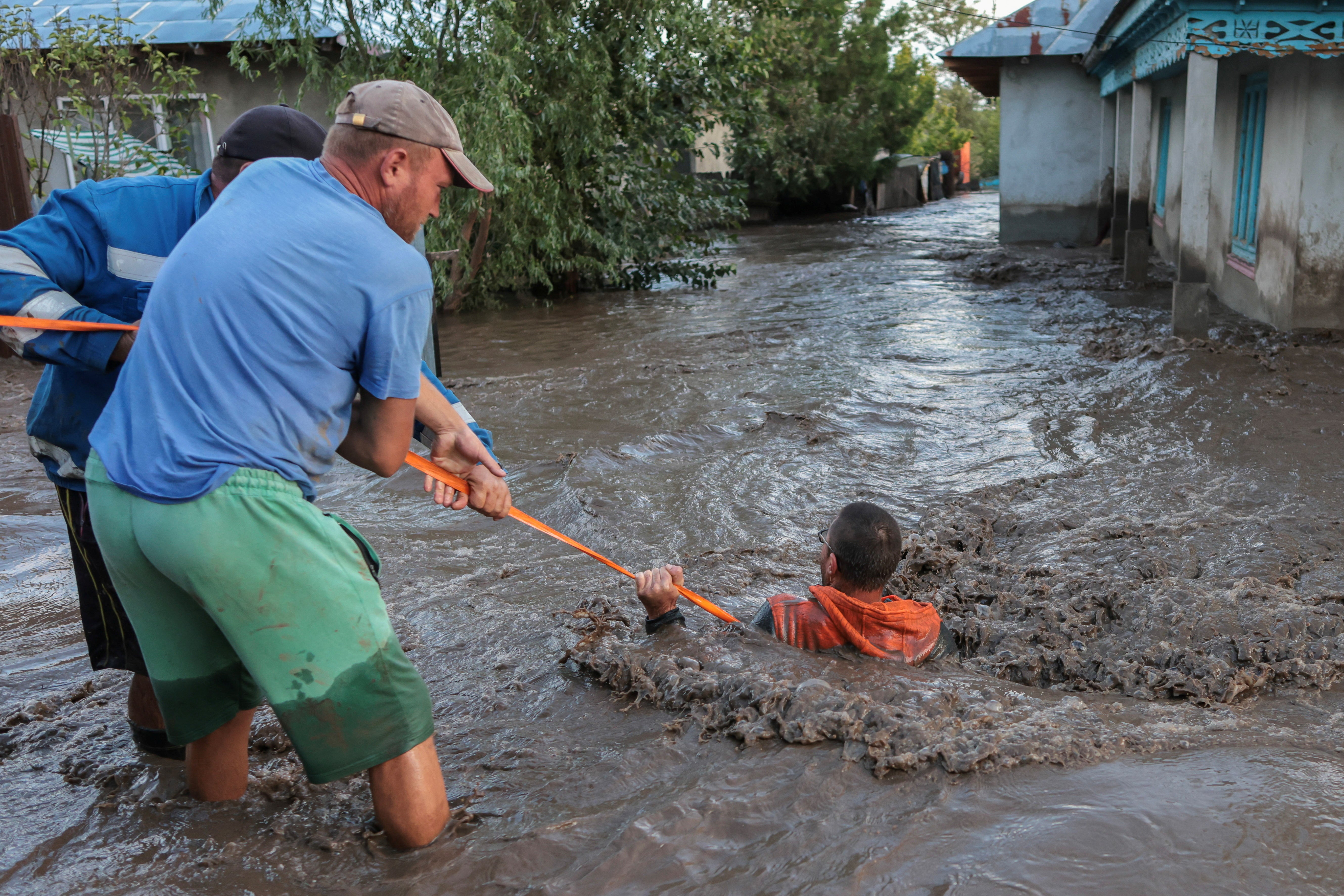 Locals and rescuers pull a man through flood water after heavy rain triggered flooding in Slobozia Conachi, Galati country, Romania