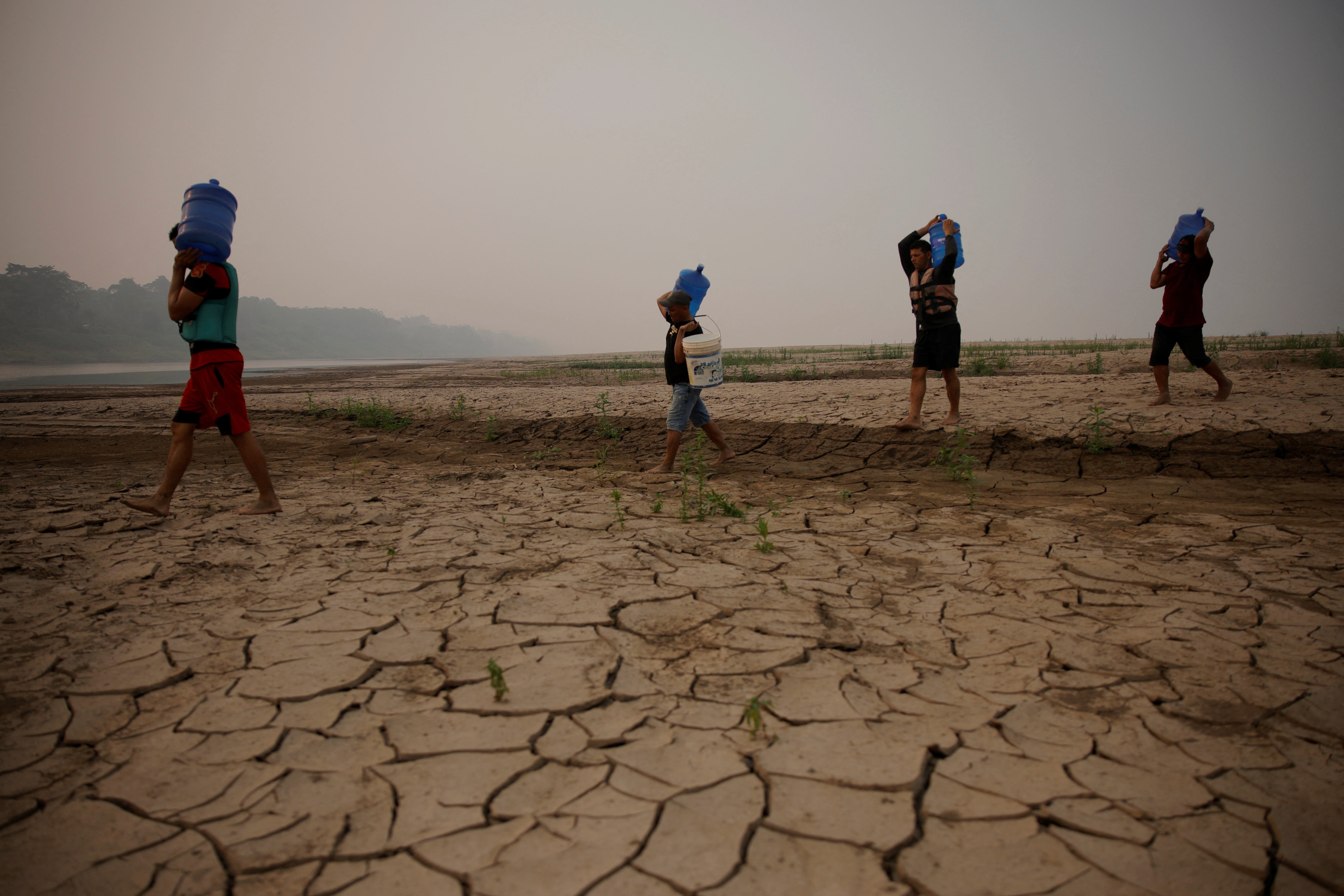 River dwellers carry water gallons, on the sandbanks of the Madeira river, to bring to the isolated region of Paraizinho community, during the worst drought of the river in history, Humaita, Amazonas state, Brazil September 8, 2024. REUTERS/Bruno Kelly