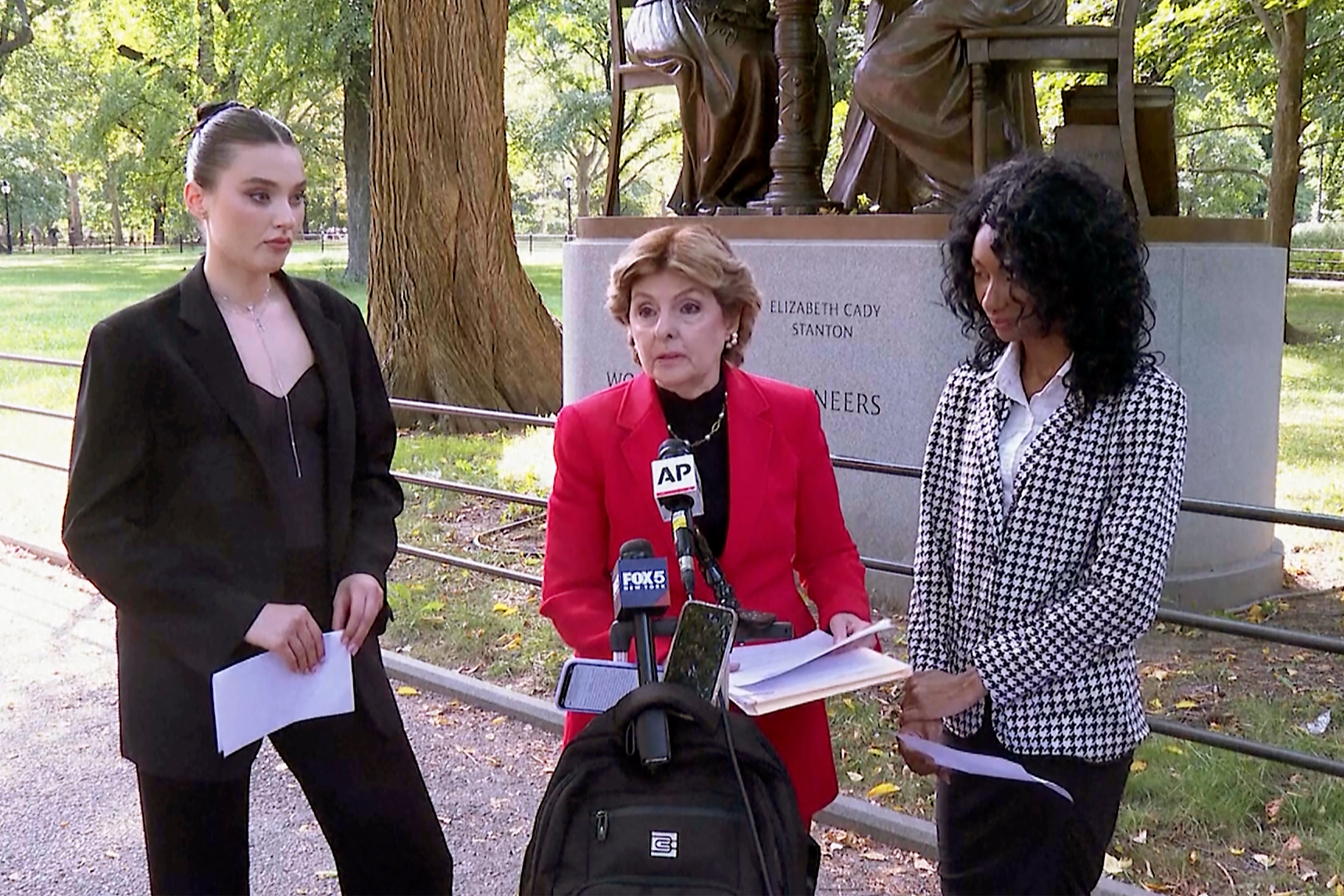 Flanked by Veronika Didusenko, left, and Danielle Hazel, right, attorney Gloria Allred, center, speaks during a news conference