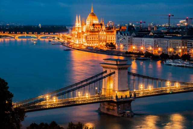 <p>A general view shows the Danube River flowing past flowing past the illuminated Hungarian Parliament Building (top) in Budapest</p>