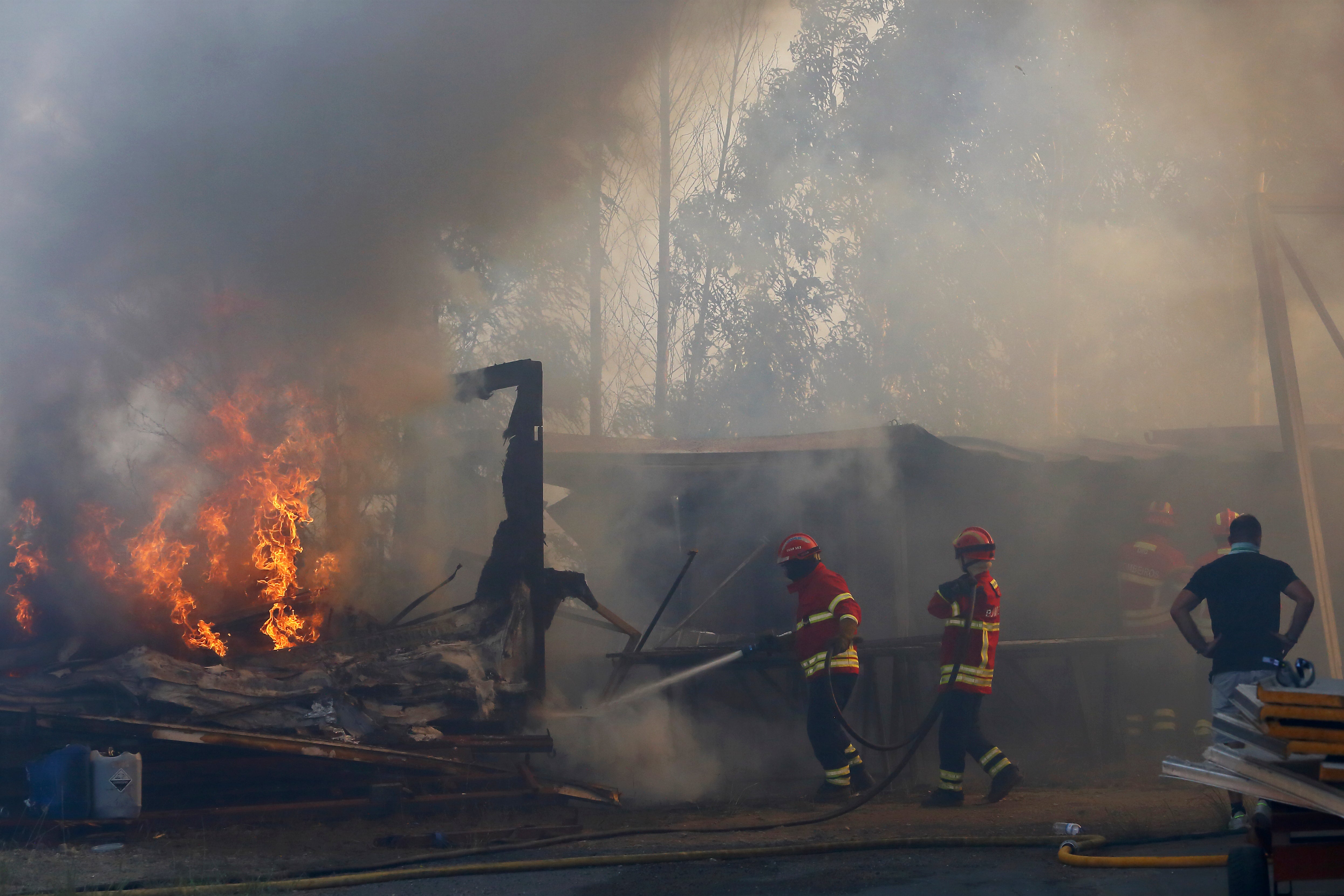 Firefighters work to control a fire next to warehouses in Sever do Vouga, a town in northern Portugal