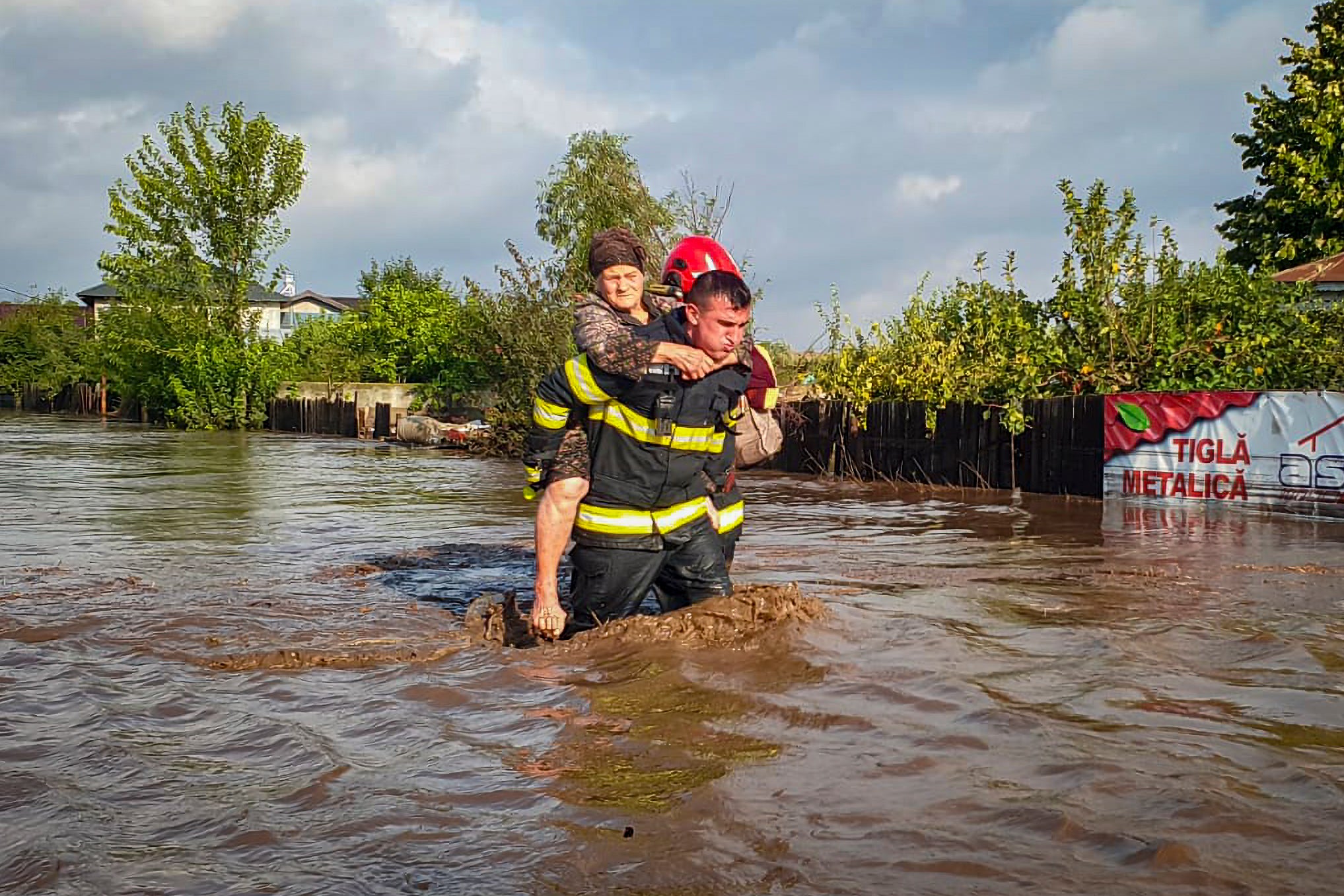 A rescuer carries a woman in Pechea, Romania