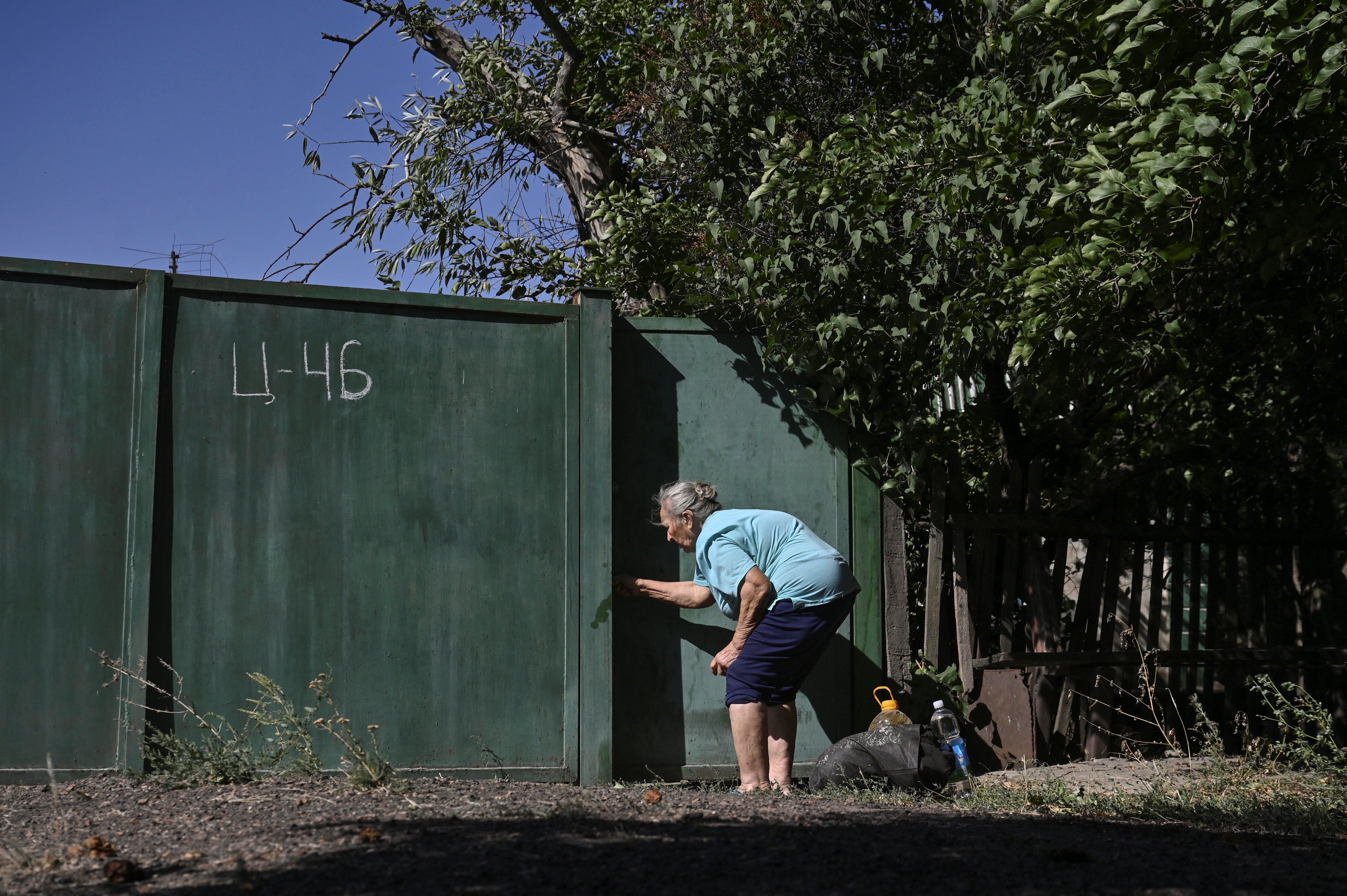 A civilian woman closes a door to her backyard during an evacuation from the outskirts of Kurakhove town