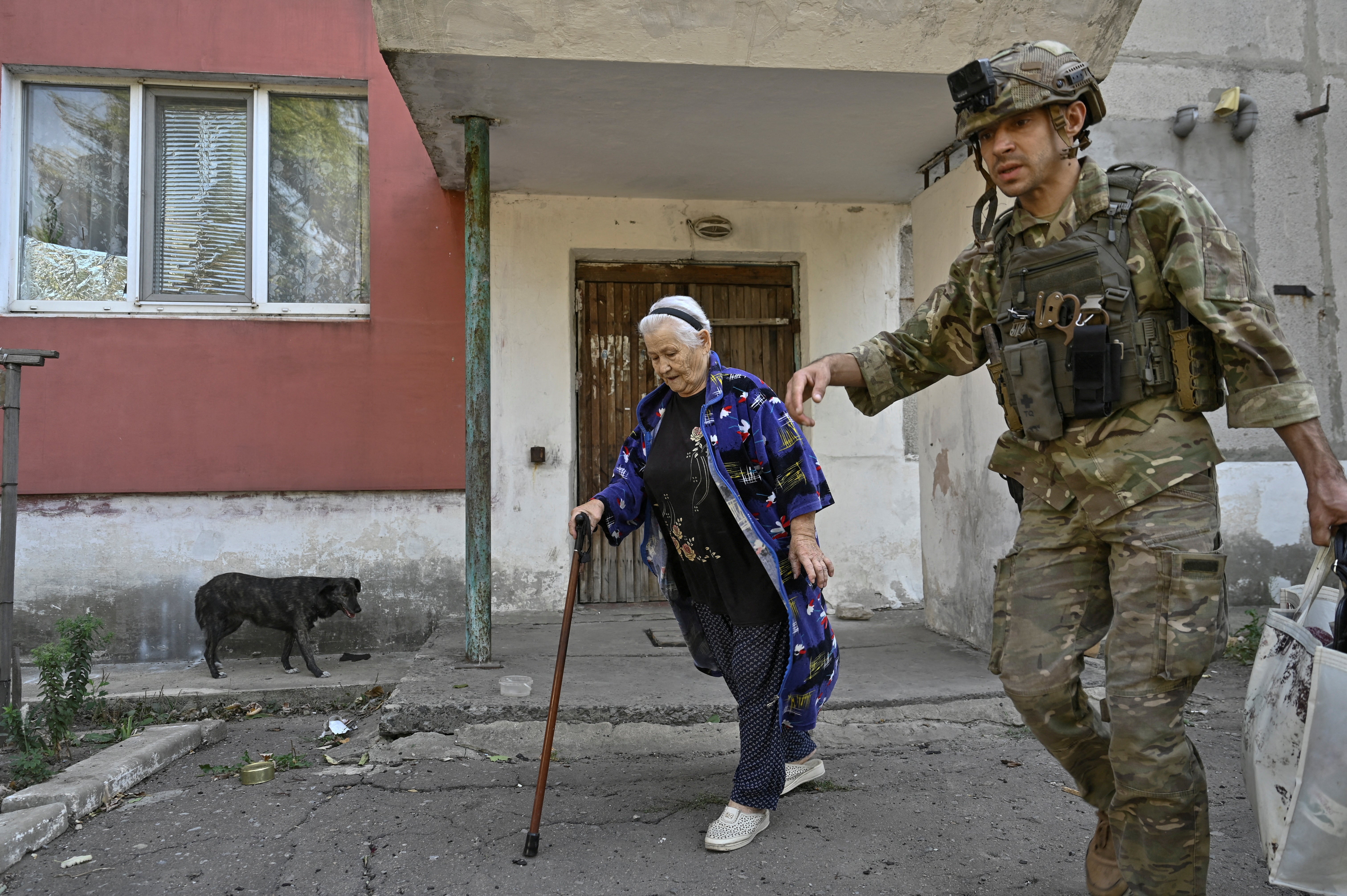 A police officer assists a civilian woman during an evacuation from outskirts of the Kurakhove town