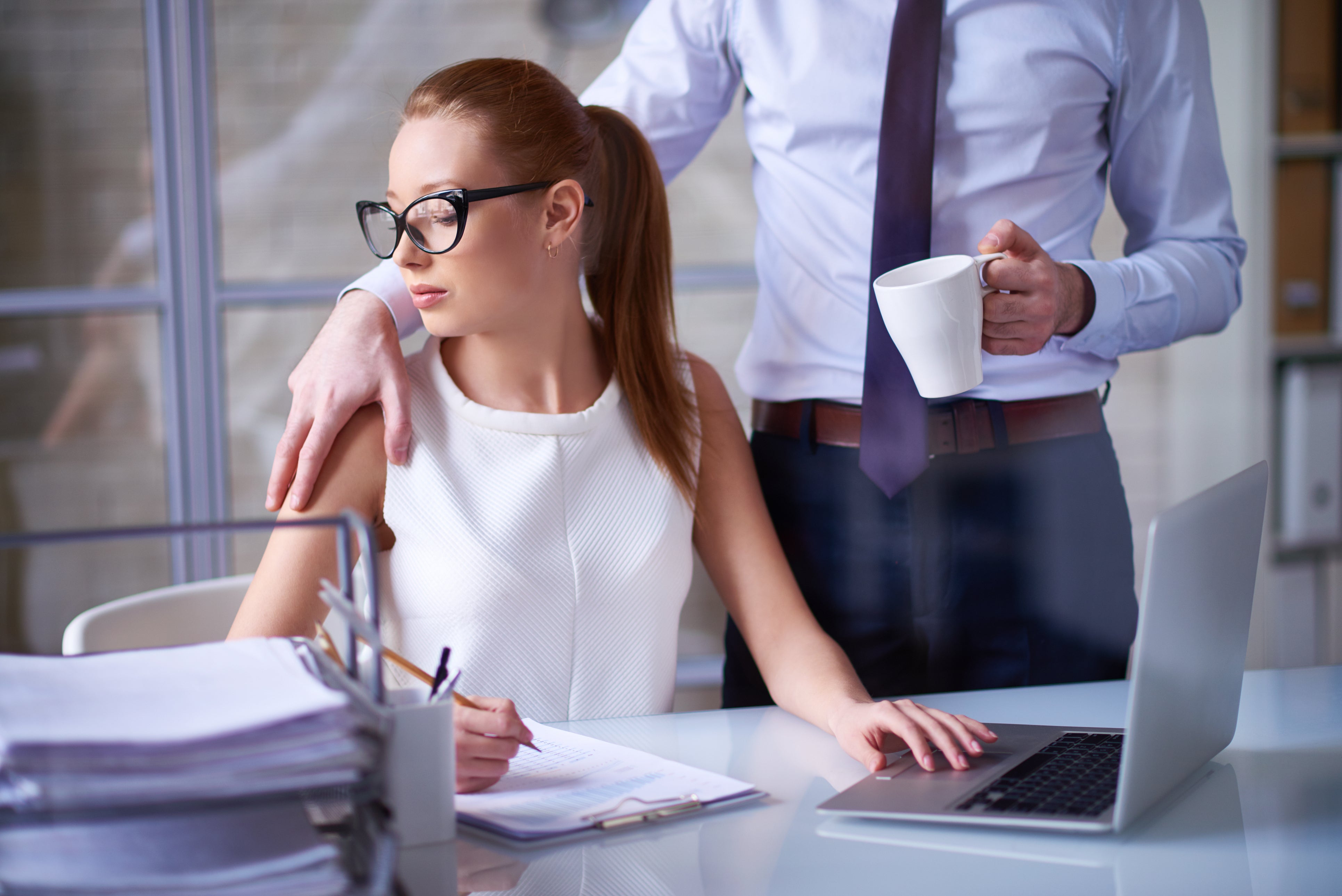 A stock photo of a man placing his hand on a woman’s shoulder at work. Women are experiencing the same rate of sexual harassment at work as they were five years ago, a new McKinsey report reveals