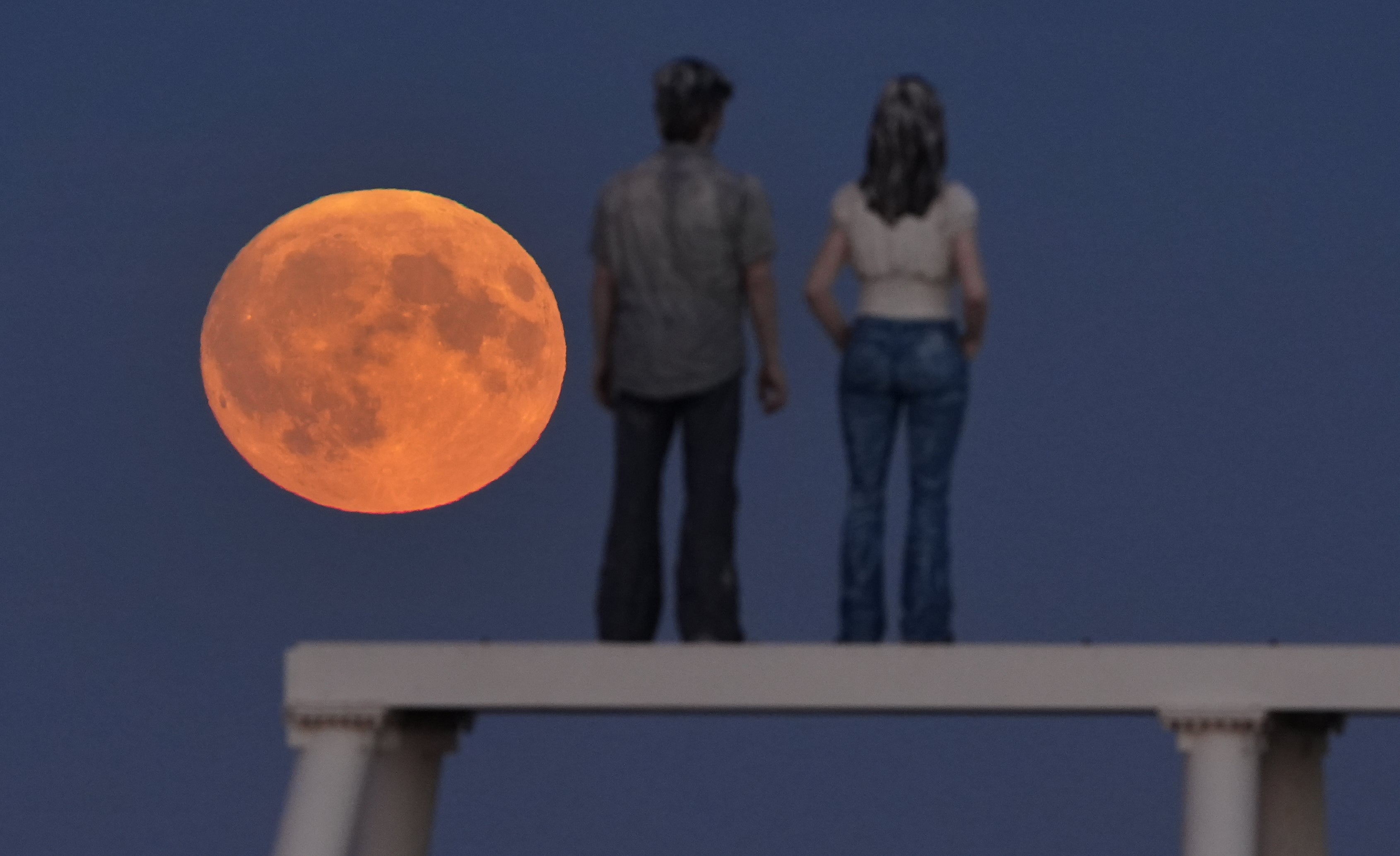 The full Harvest moon rises over 'The Couple' sculpture at Newbiggin-by-the-Sea in Northumberland