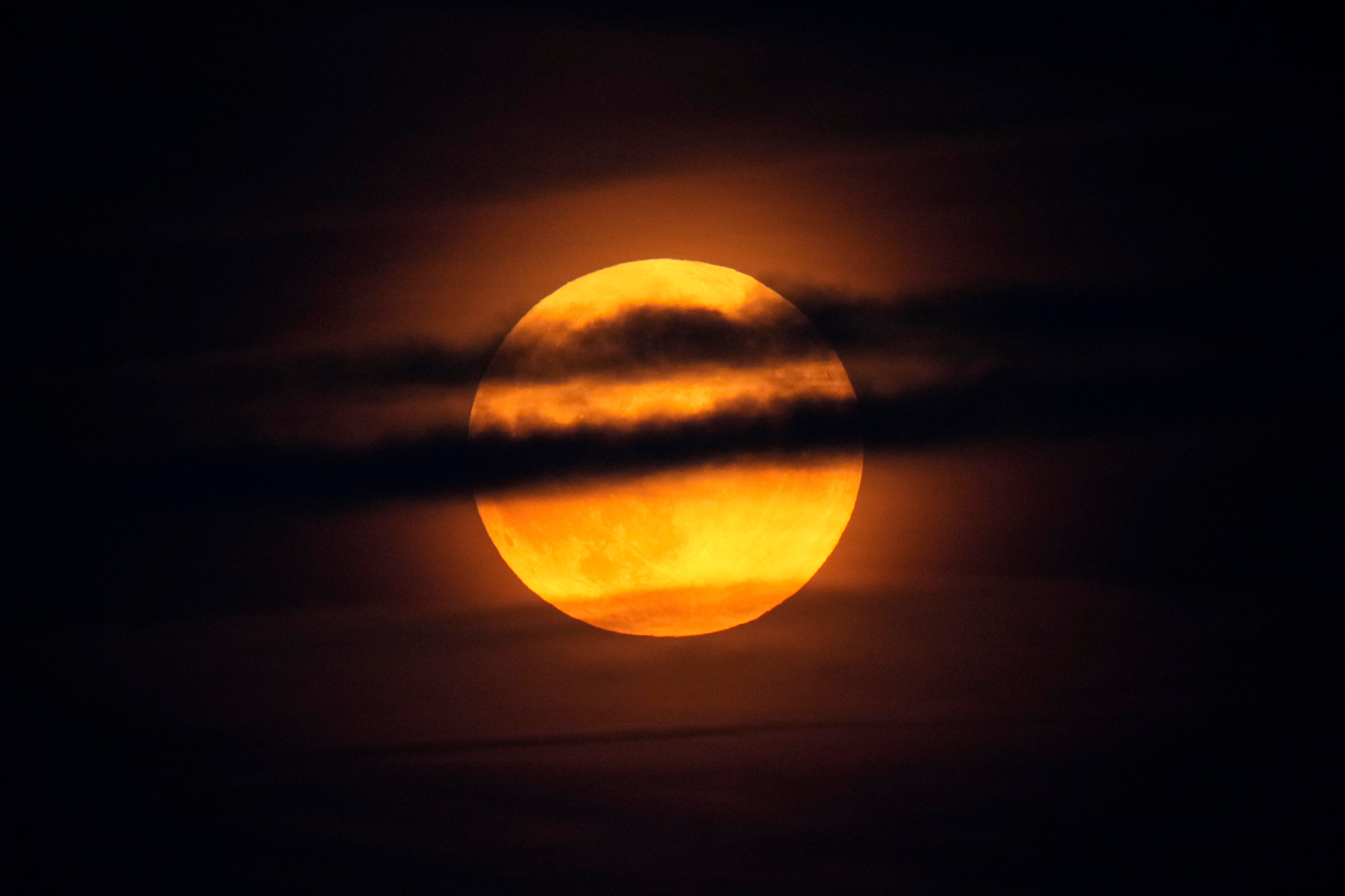 The moon rises through clouds over the Atlantic Ocean off the coast of Camden, Maine, USA