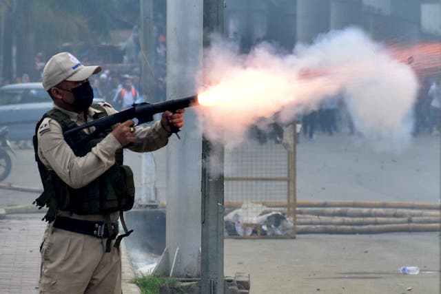 <p>A police officer fires a tear smoke shell to disperse demonstrators during a protest march, in Imphal</p>