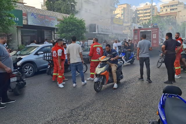 <p>People gather as smoke rises from a mobile phone shop in Sidon, Lebanon </p>