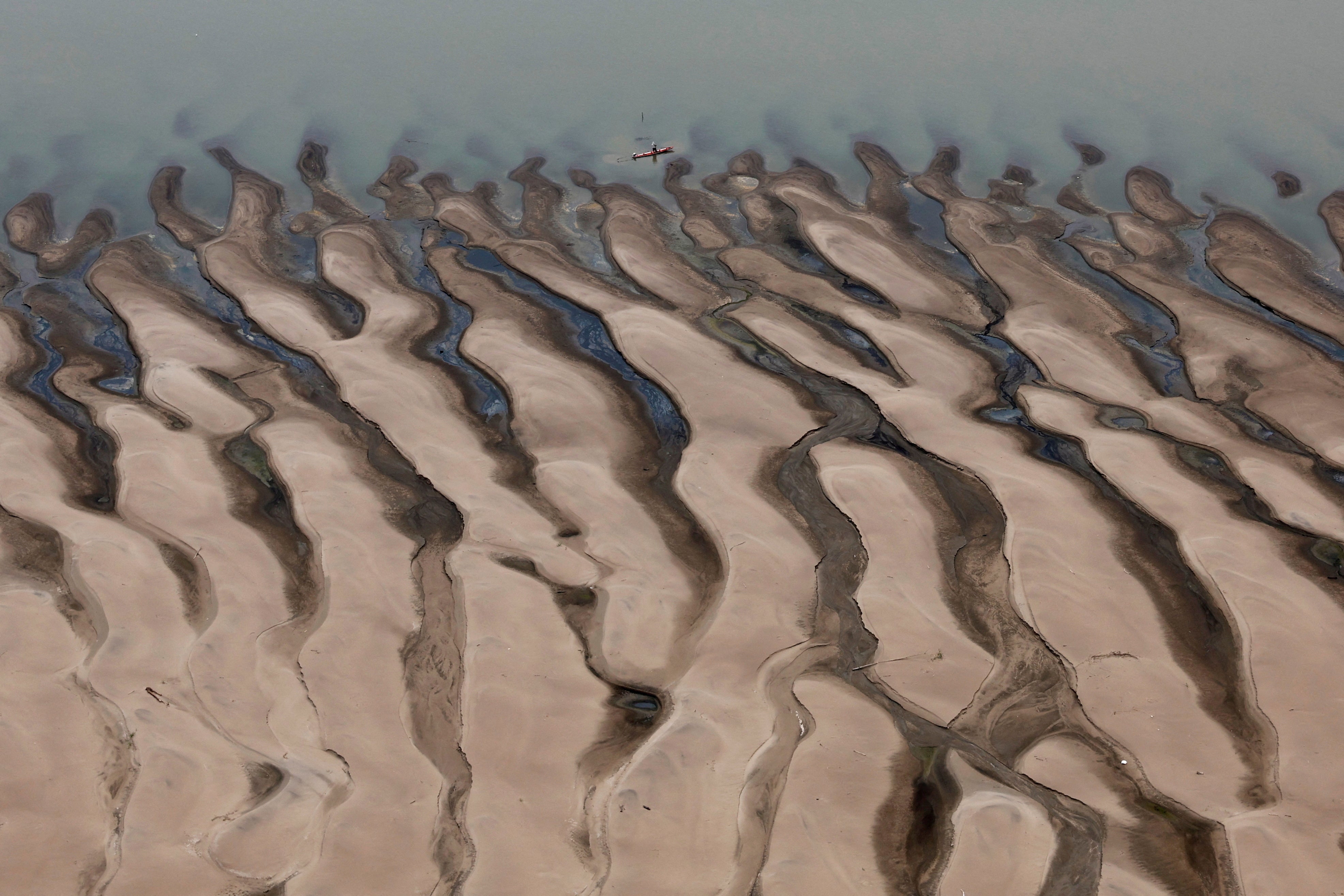 A man rides a boat in front of the Solimoes River sandbanks, one of the largest tributaries of the Amazon River on Tuesday. Some parts are dried up completely.