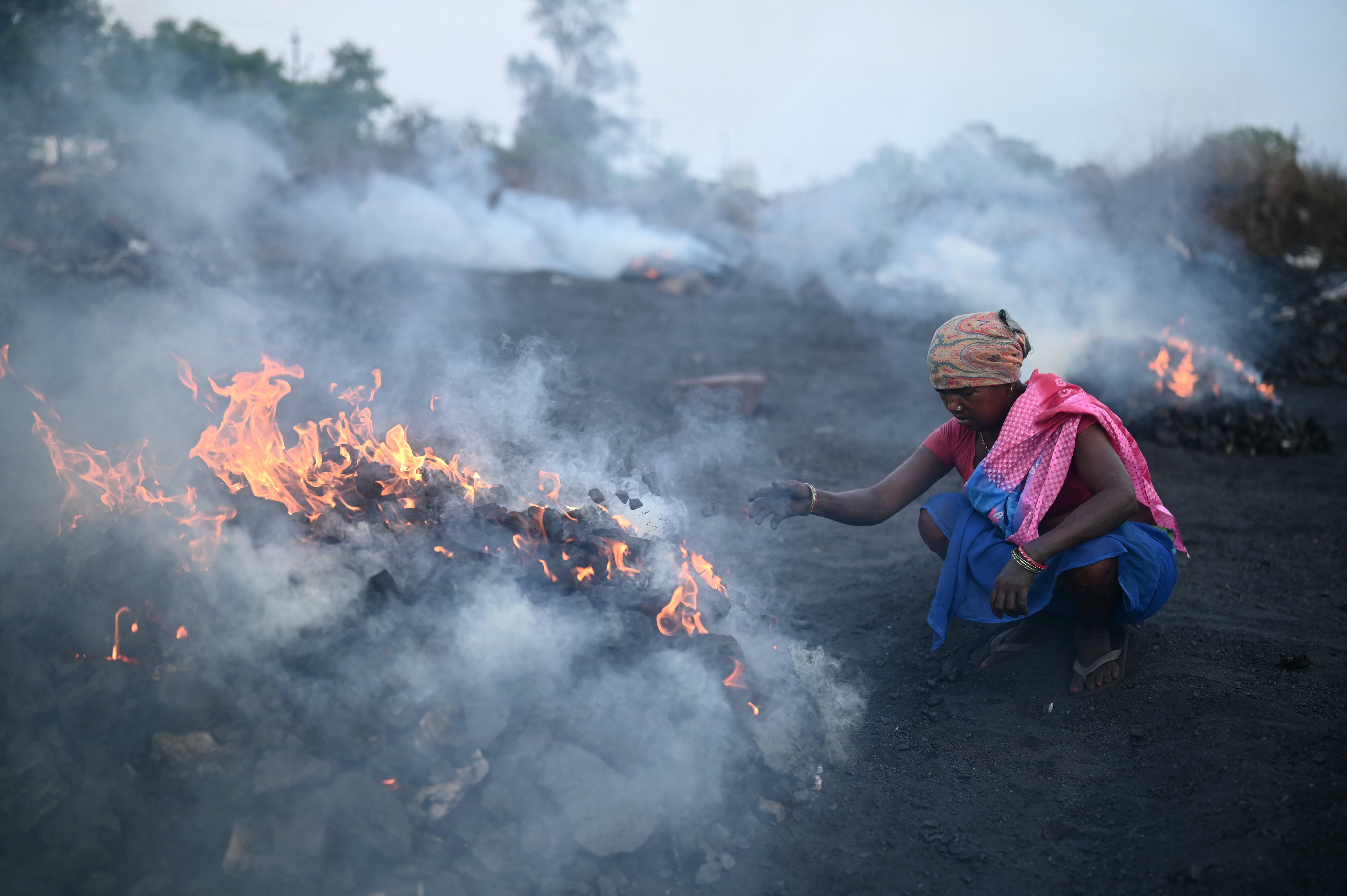 Coal picker burns raw coal at a mine in Jharia on the outskirts of Dhanbad in India’s Jharkhand state