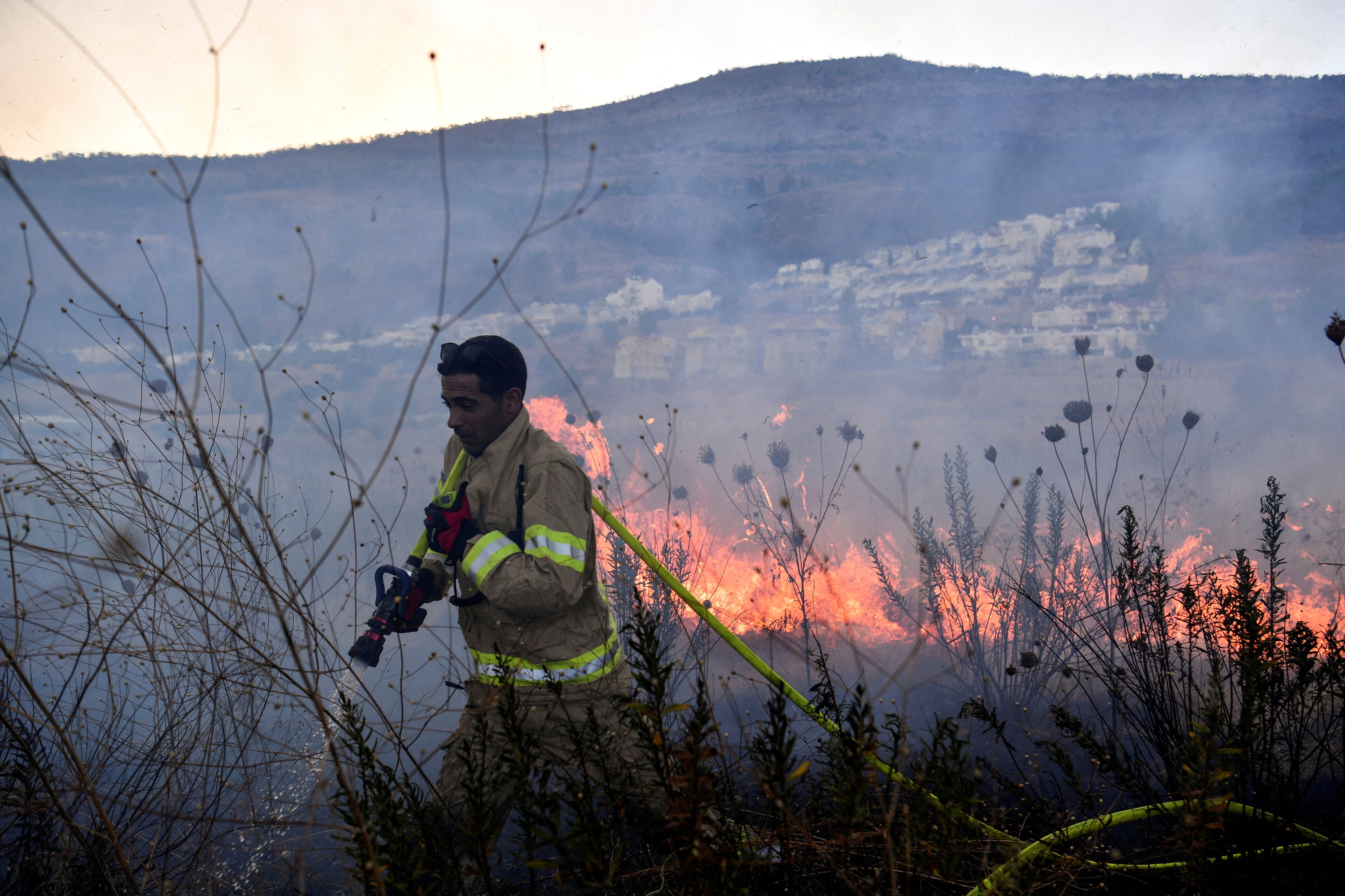 A firefighter works to put out a blaze after rockets were fired from Lebanon towards Israel, amid cross-border hostilities between Hezbollah and Israel, in Kiryat Shmona, northern Israel 18 September 2024