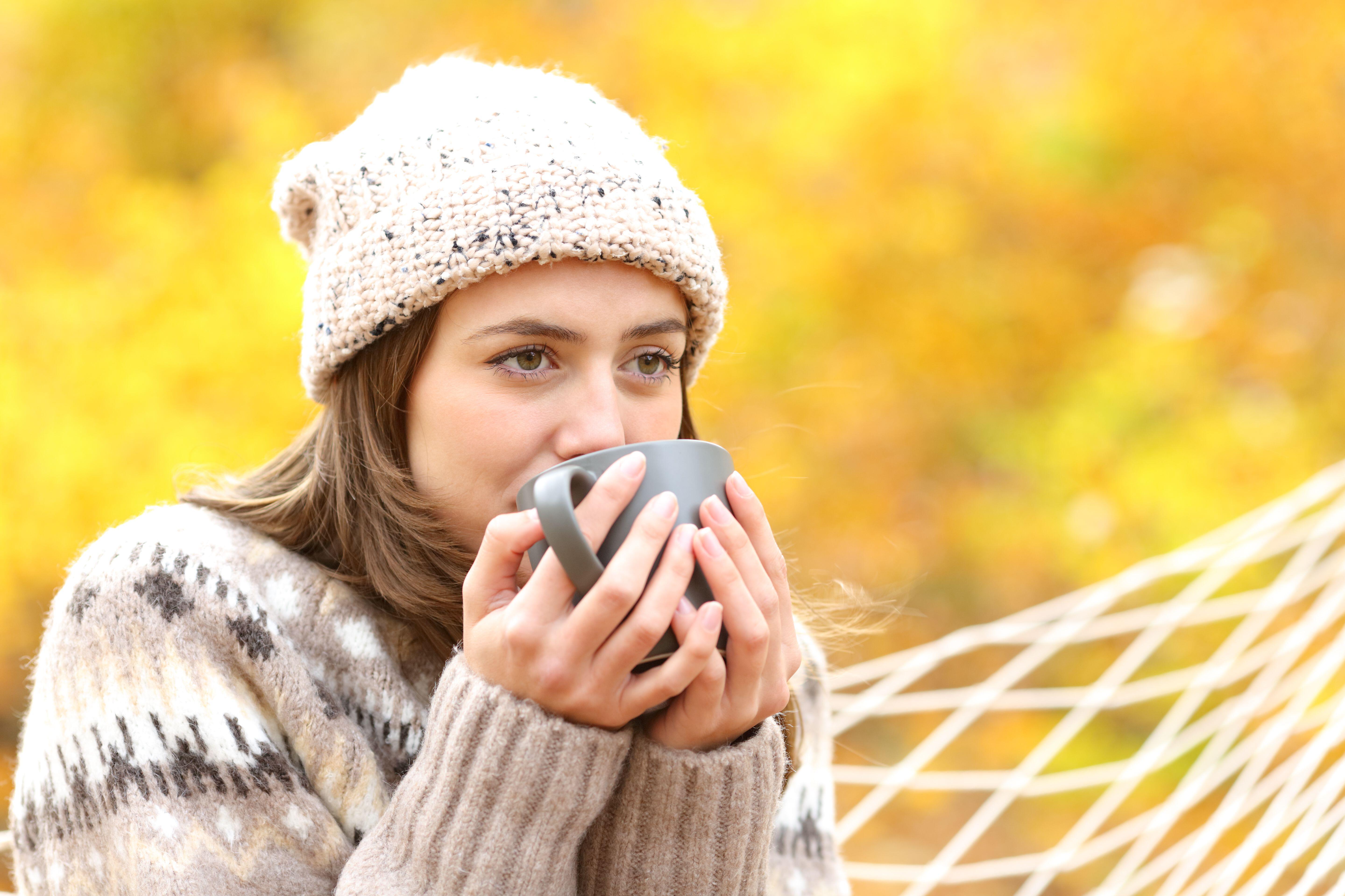 A woman drinking coffee in a hammock during the autumn (Alamy/PA)