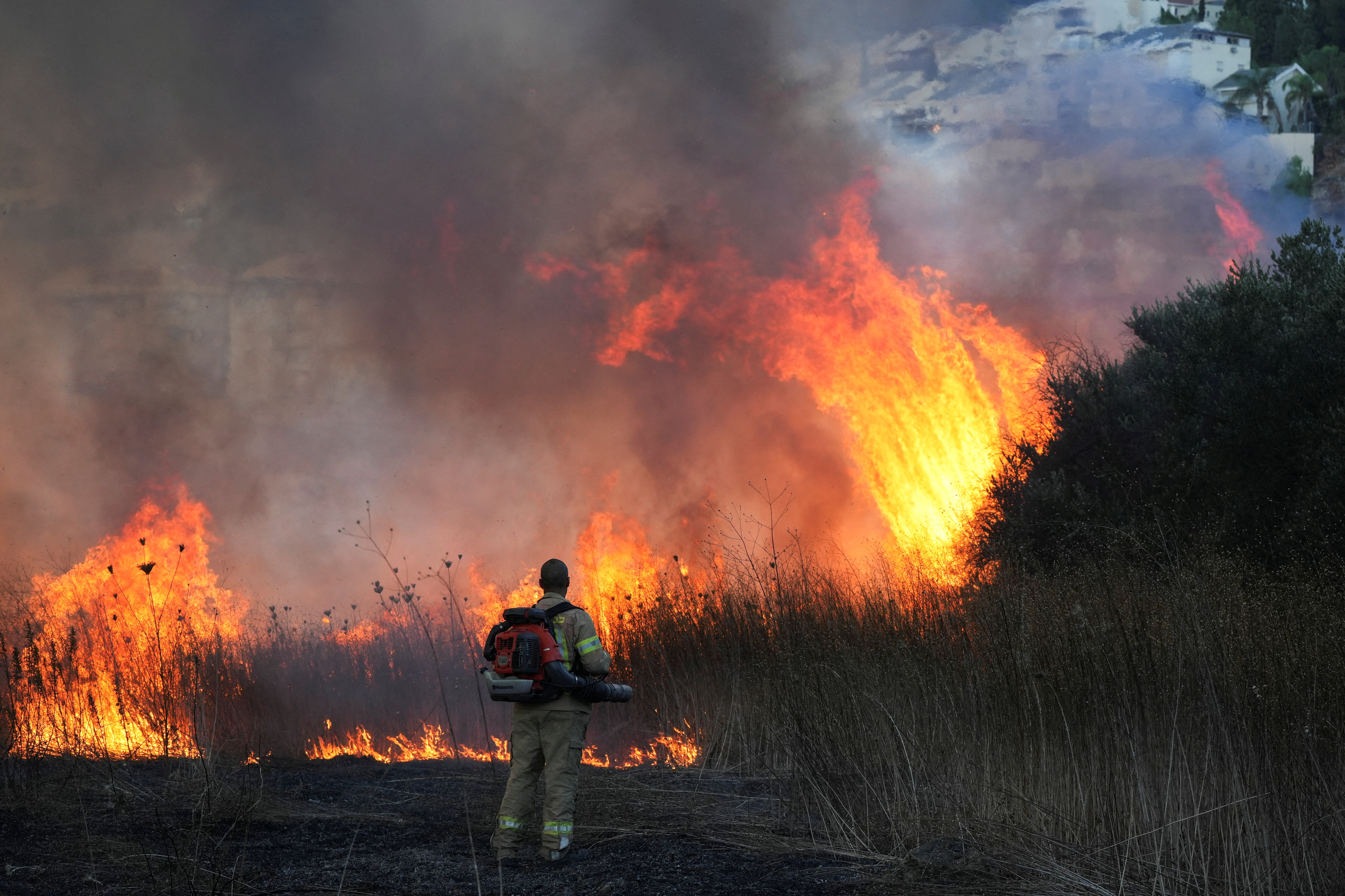 A firefighter works to put out a blaze after rockets were fired from Lebanon towards Israel