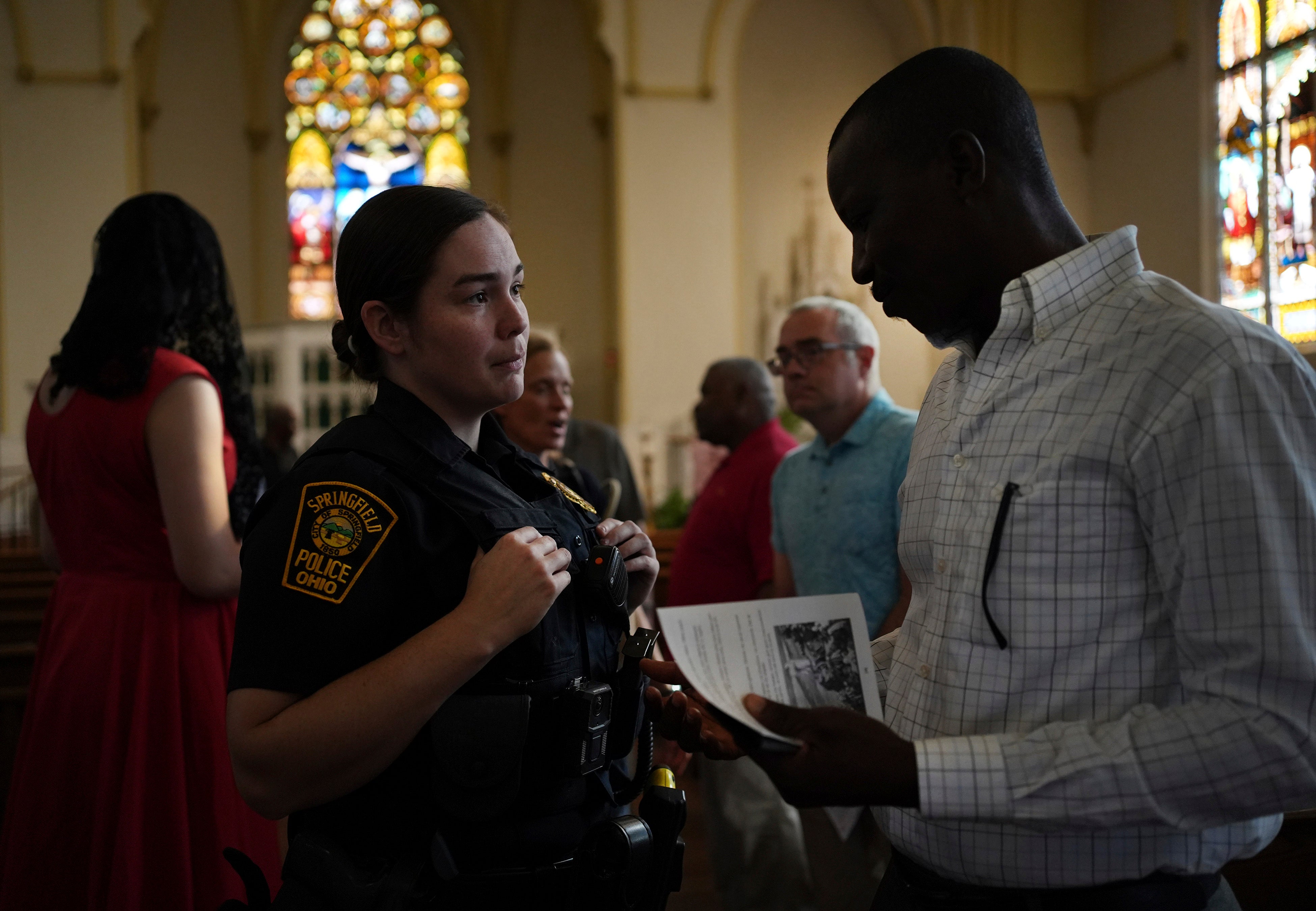 A Springfield police officer speaks with a community member following a church service in support of the Haitian community. As Trump and his allies spread untrue rumors about the city, Haitian residents say they’re afraid for their safety