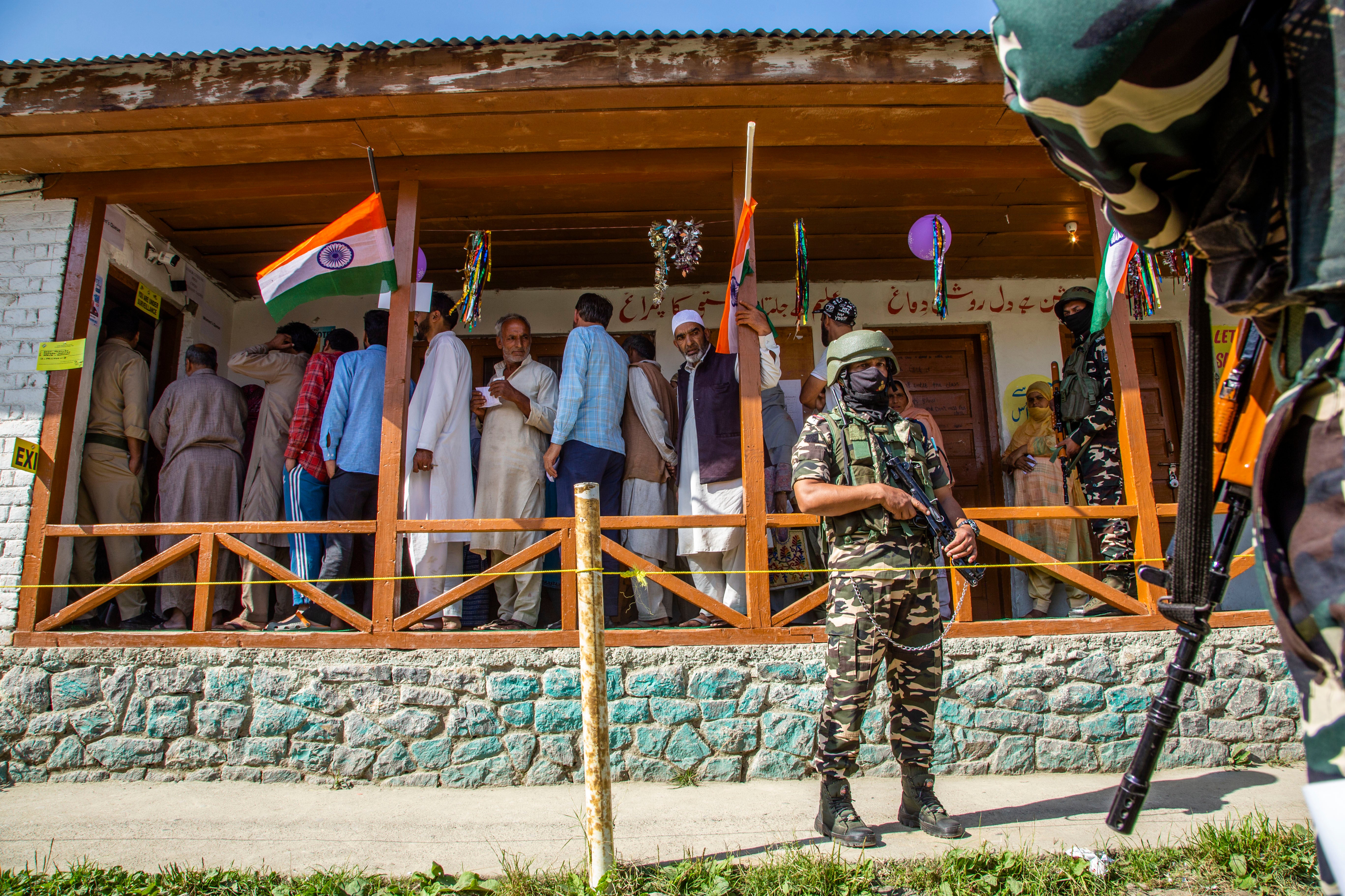 Indian paramilitary soldiers stand guard as Kashmiris wait to cast their votes inside a polling station on 18 September 2024 in Pulwama south of Srinagar, India