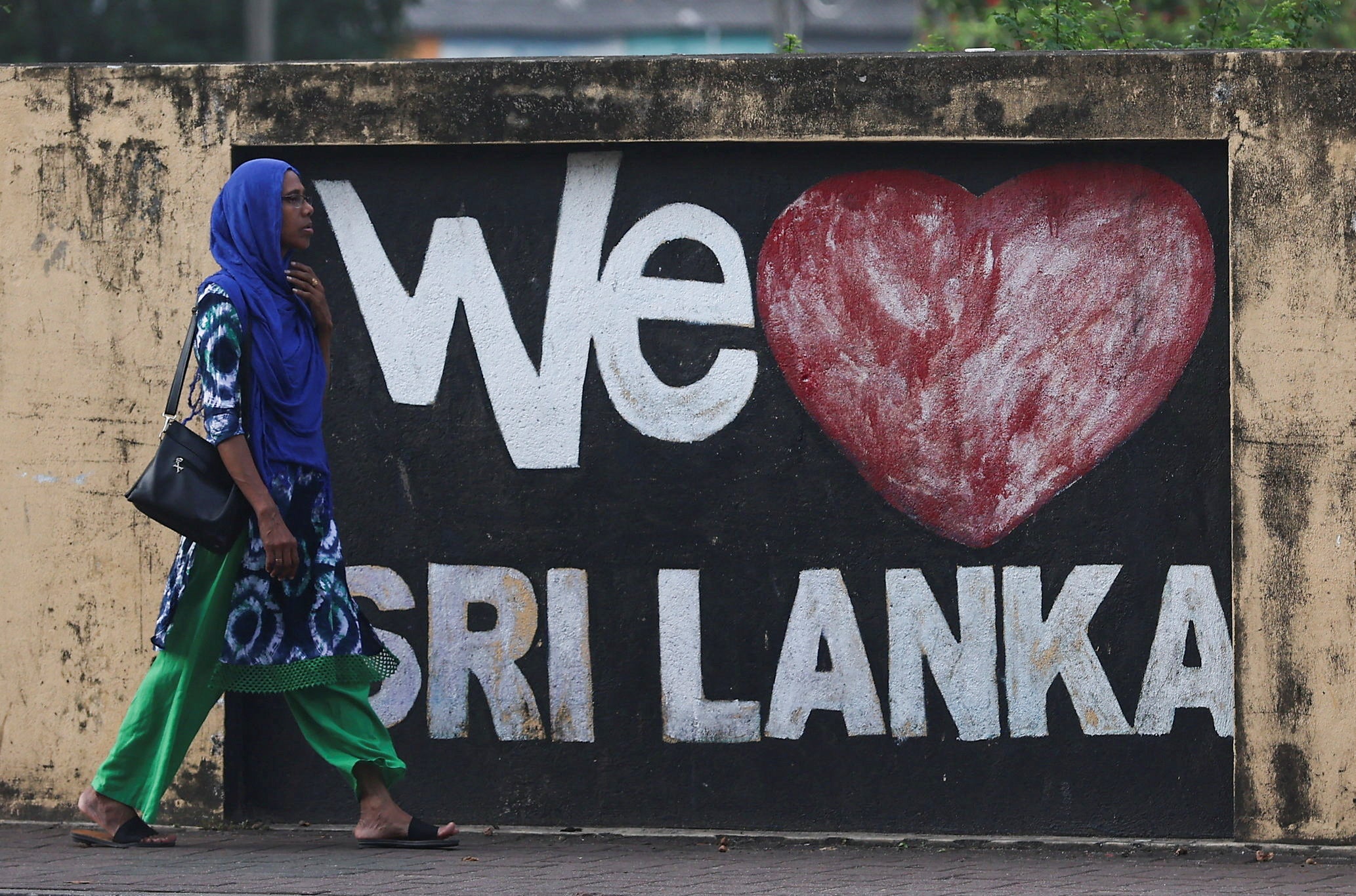 A woman walks past graffiti on a wall along a main road, ahead of the upcoming presidential election scheduled for 21 September