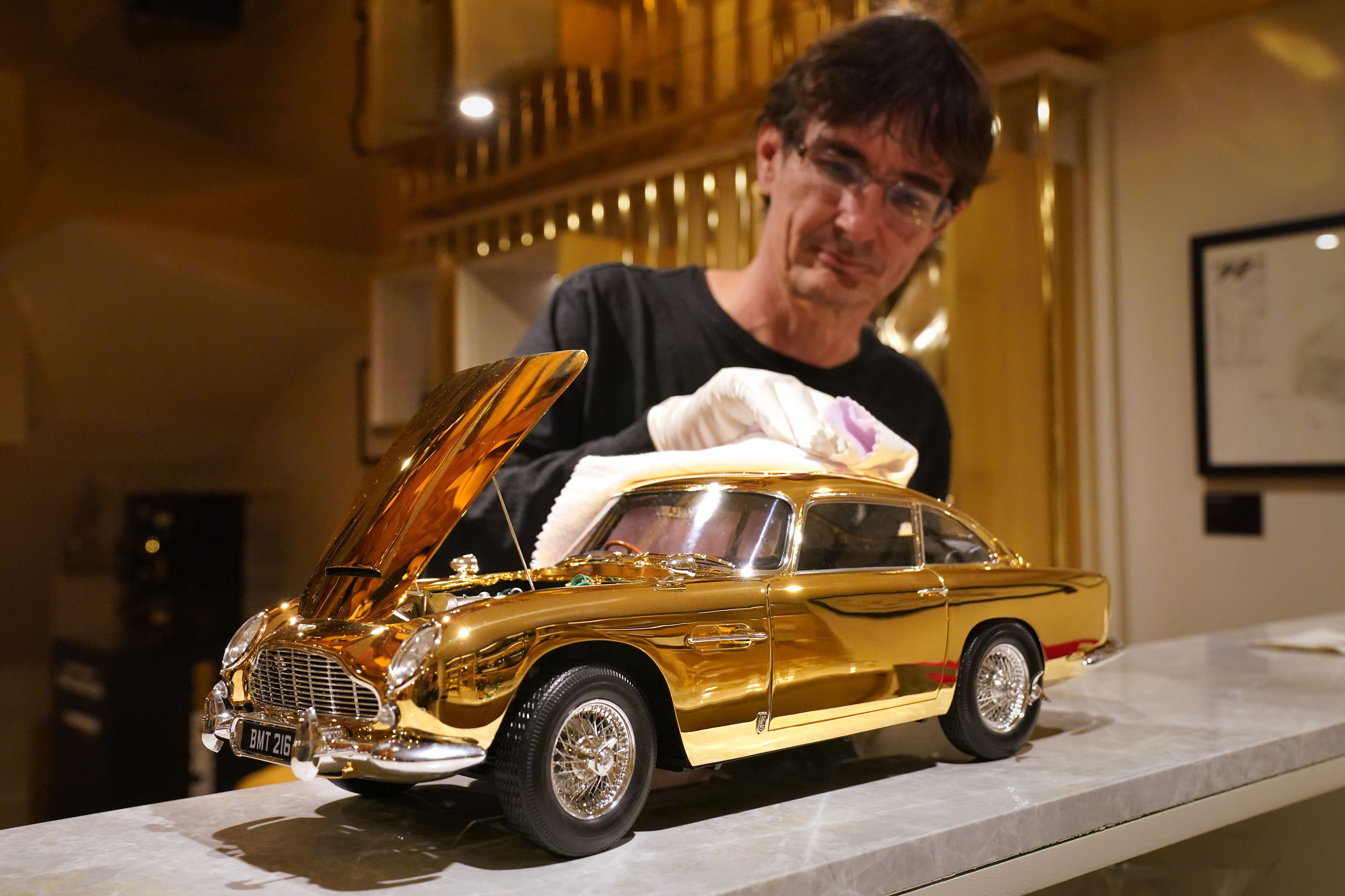 Agora Models chief executive James Franks polishes a 24-carat gold-plated model of James Bond’s Aston Martin DB5, priced at £24,999 (Jonathan Brady/PA)