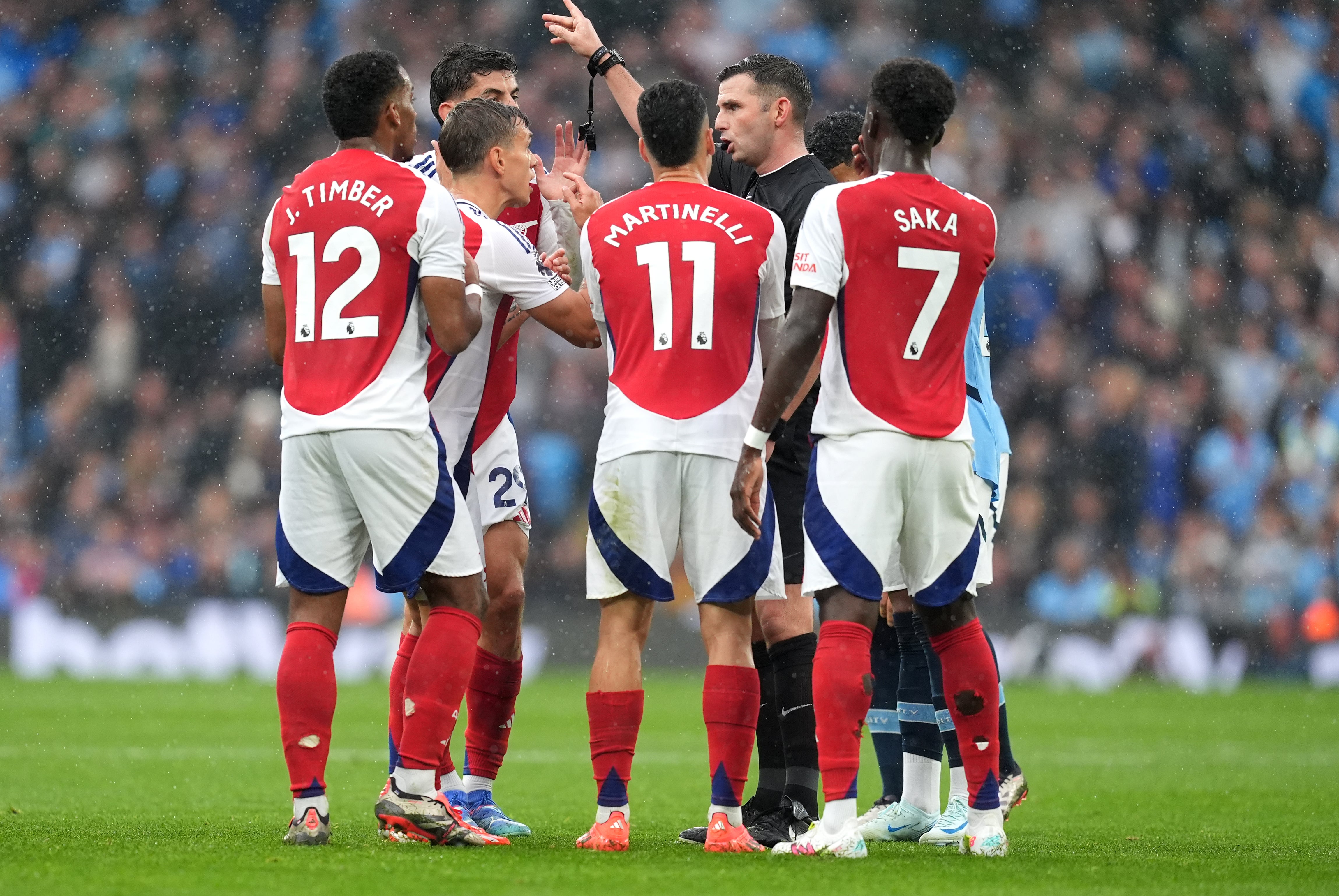 Leandro Trossard e jogadores do Arsenal reclamam com Michael Oliver durante a partida.