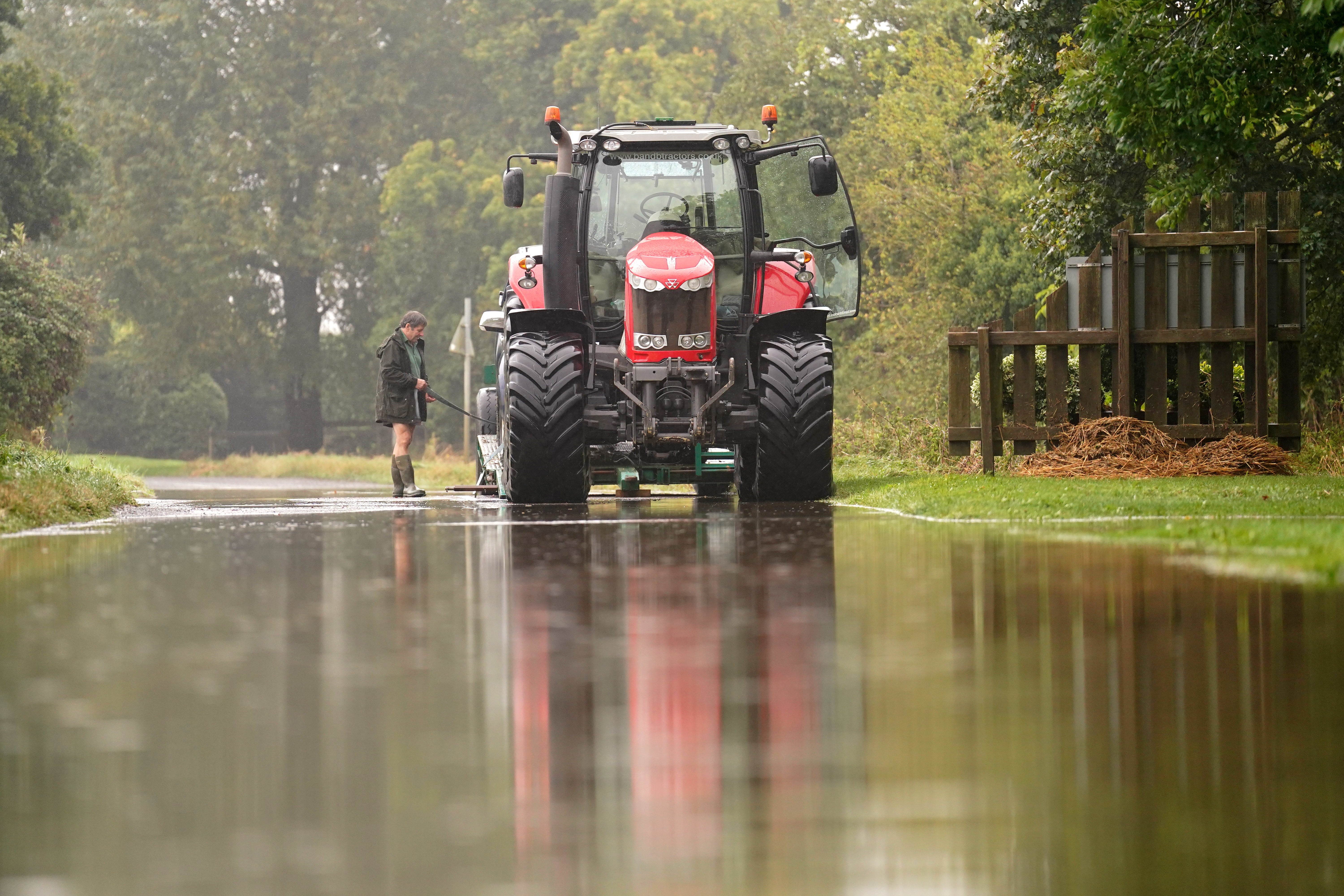 A tractor pulling a vehicle which is stuck in flood water in Grendon, Northamptonshire