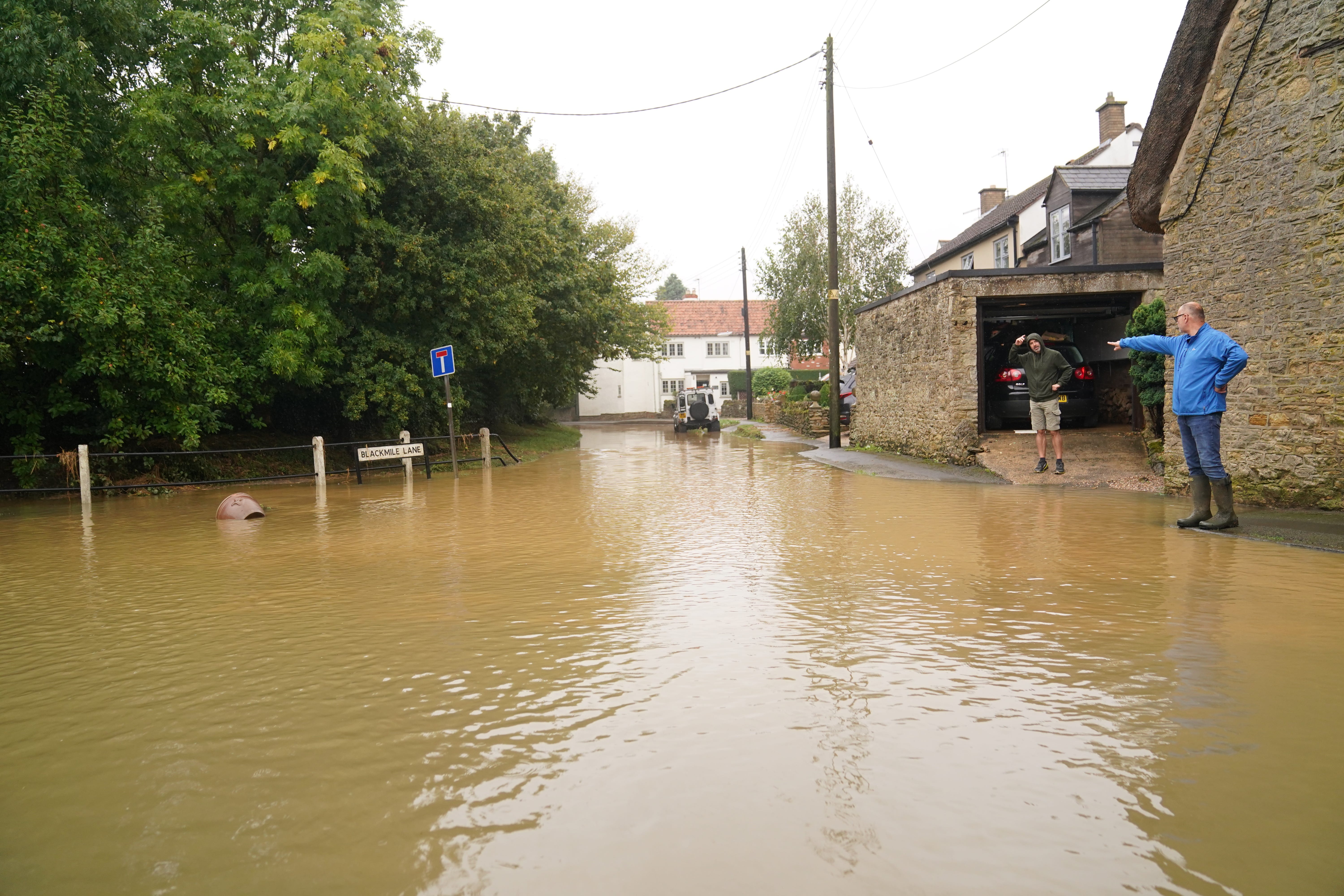 People looking at floodwater in Grendon, Northamptonshire(Joe Giddens/PA)