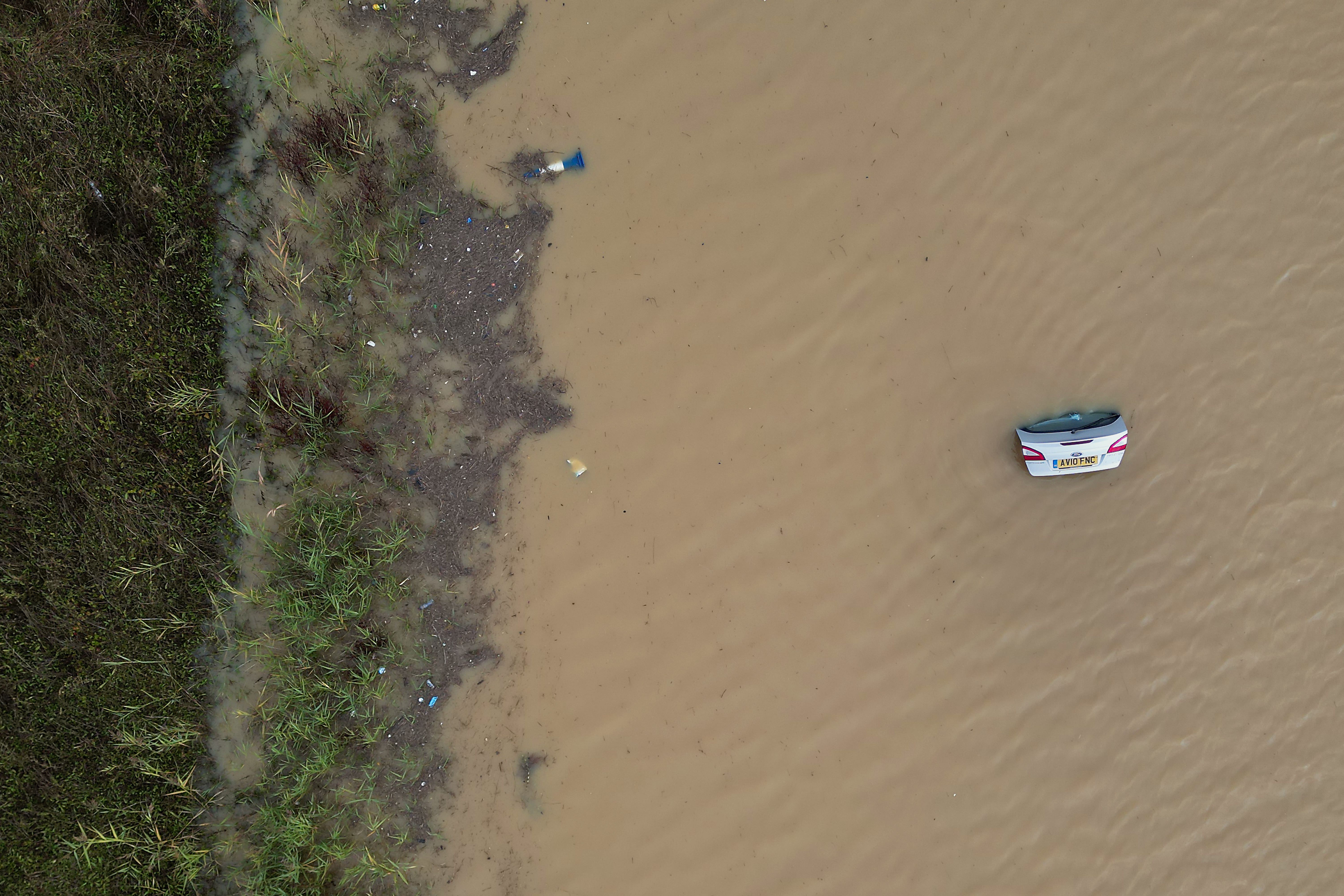 The open boot of a car is visible above the water where the vehicle is submerged in flood water on the A421 in Marston Moretaine, Bedfordshire (Joe Giddens/PA)