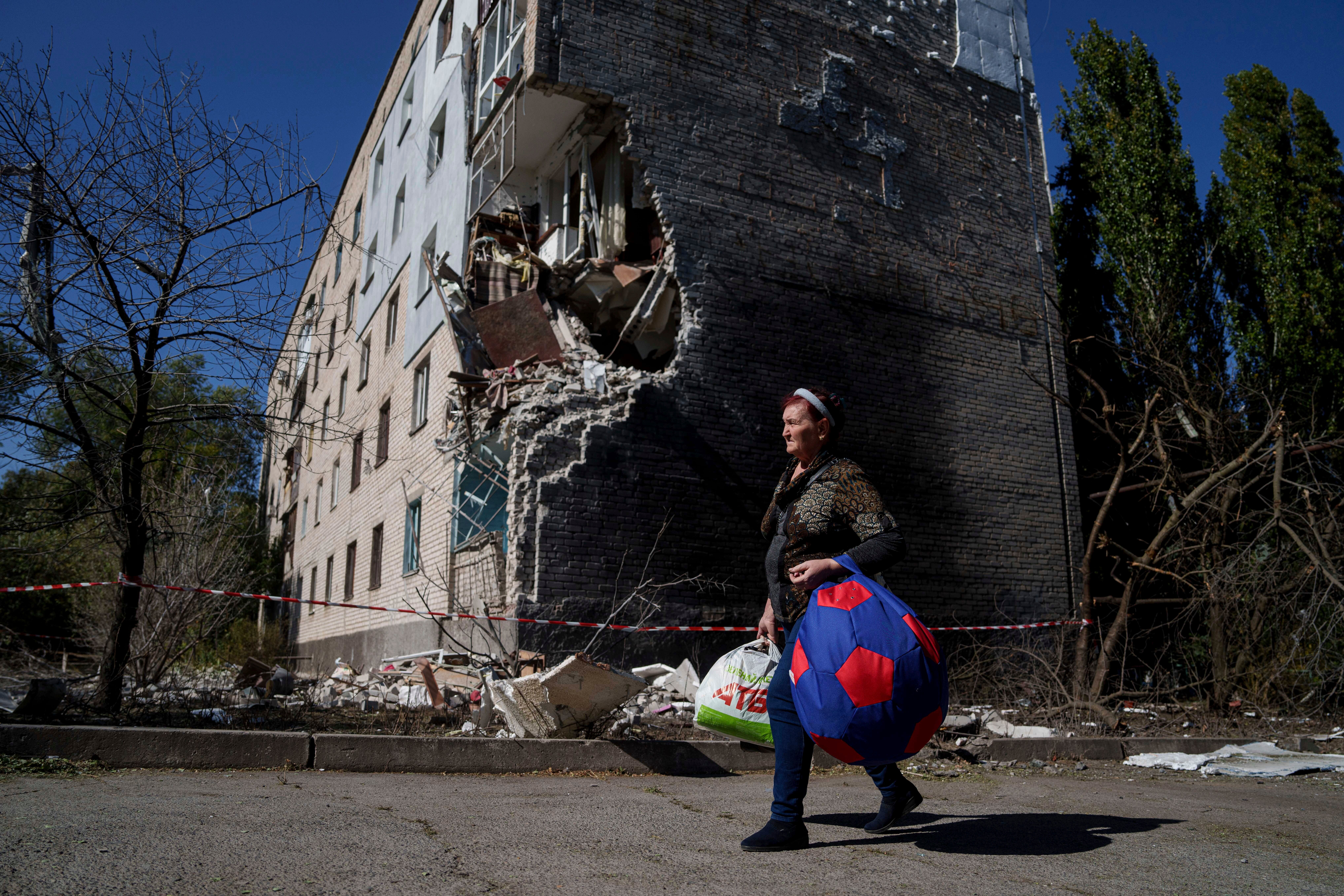 A local woman carries her belongings from a residential building which was hit by a Russian bomb in Mykolaivka, Donetsk region, Ukraine