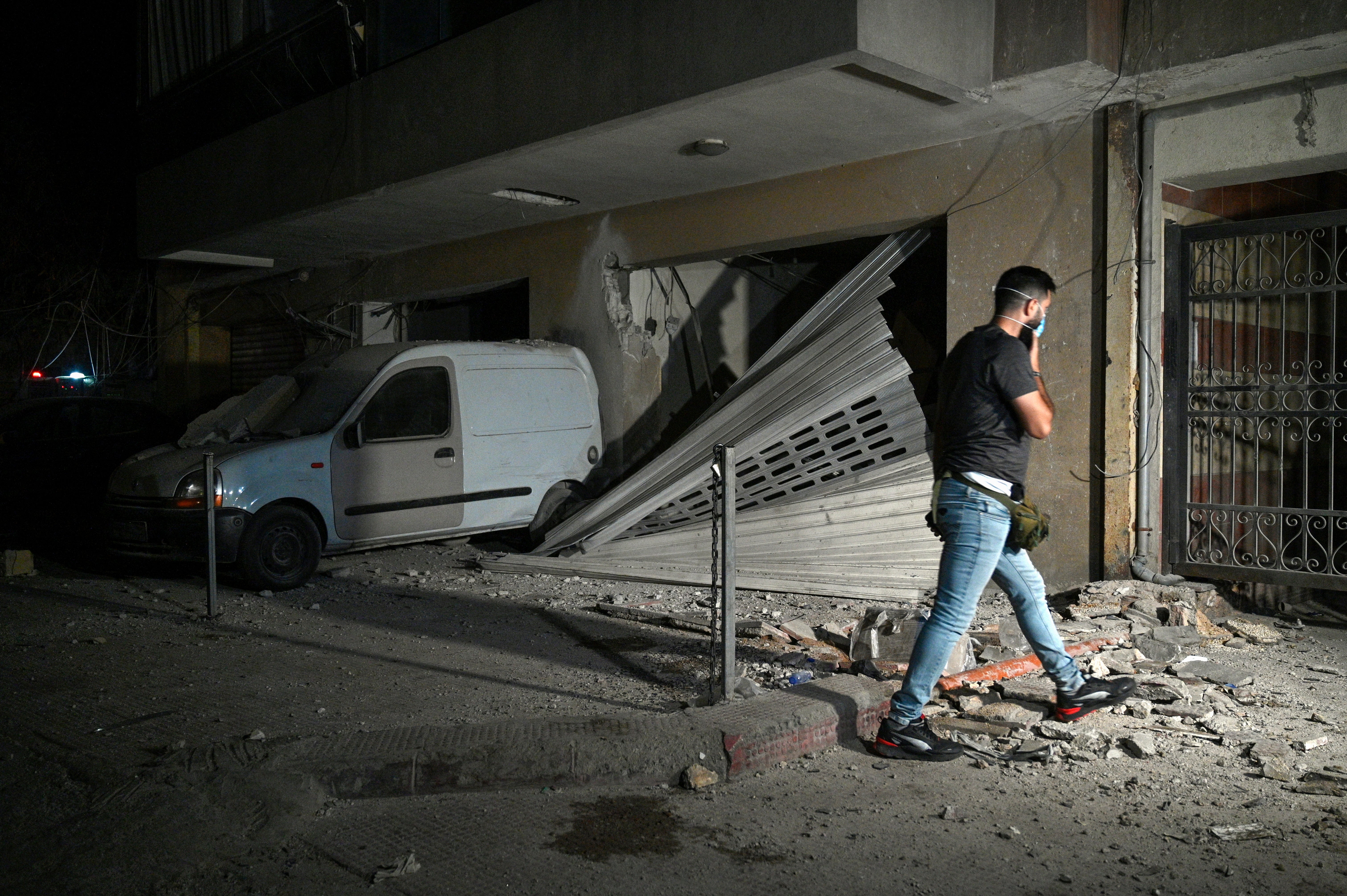 A man walks next to a damaged vehicle at the southern suburb of Beirut after an Israeli military strike, in Beirut, Lebanon, 23 September 2024