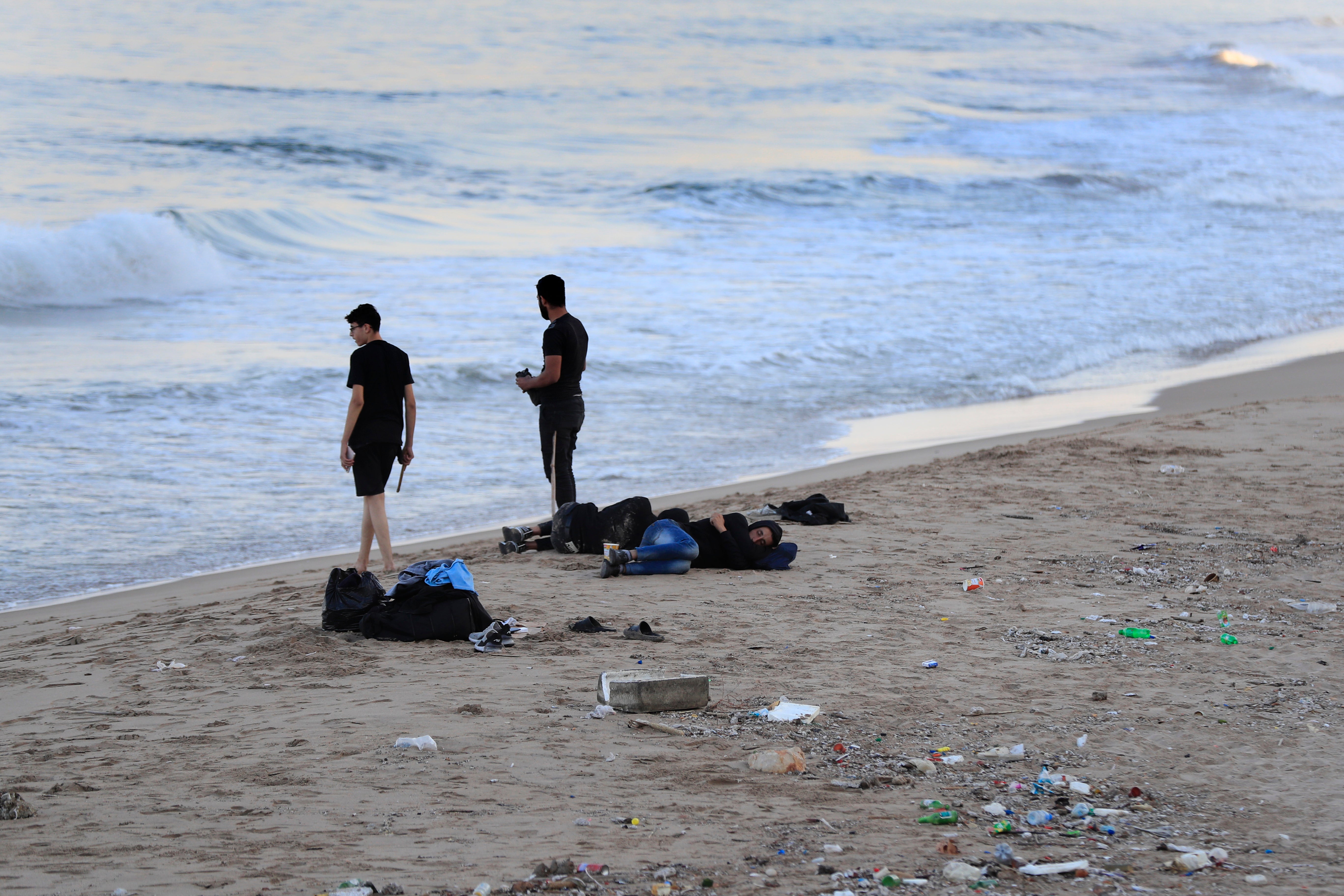 Lebanese men who fled on the southern villages amid ongoing Israeli airstrikes Monday sleep on a public beach in the southern port city of Sidon, Lebanon