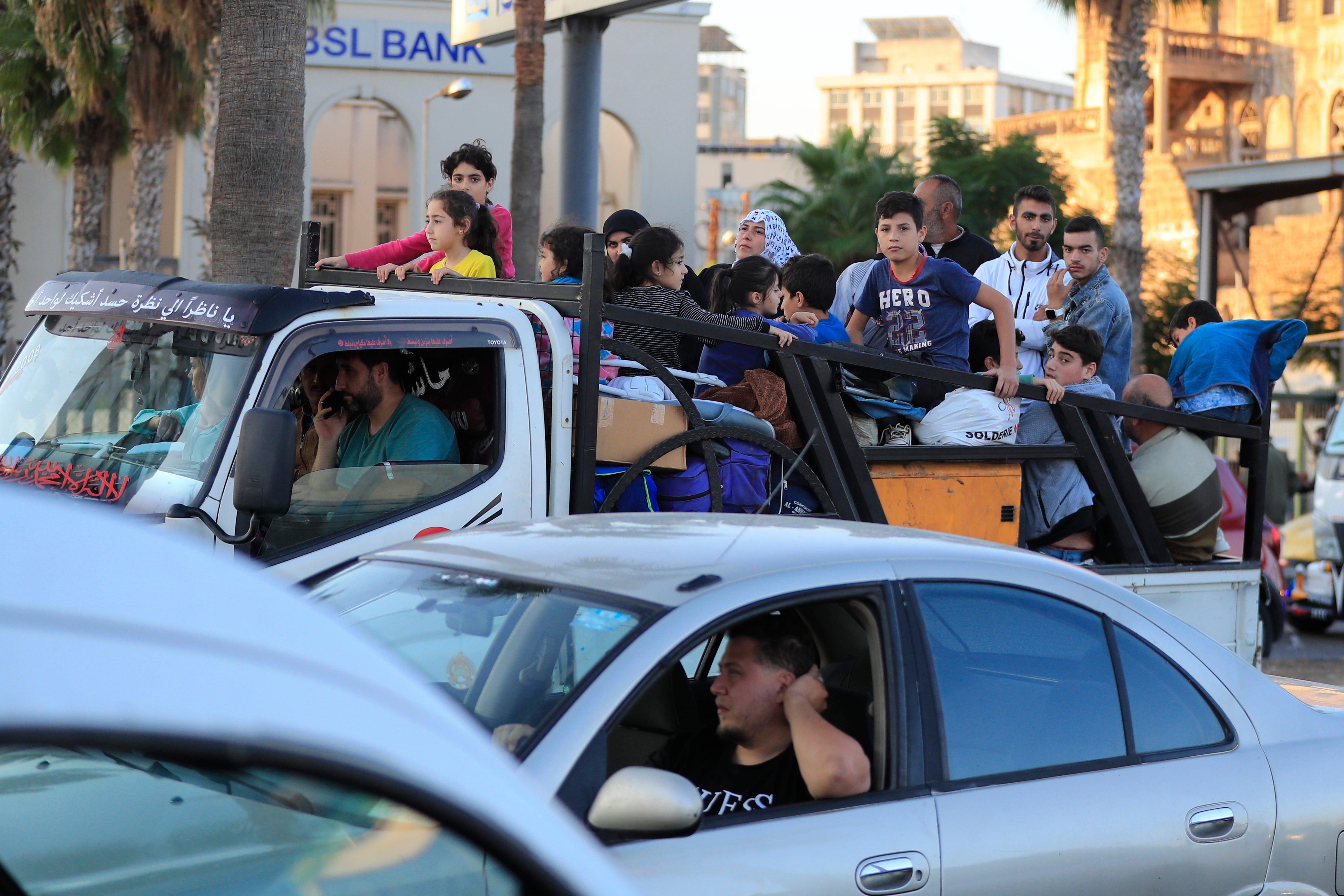 Lebanese citizens who fled the southern villages amid ongoing Israeli airstrikes Monday, sit on their cars at a highway that links to Beirut city, in the southern port city of Sidon, Lebanon