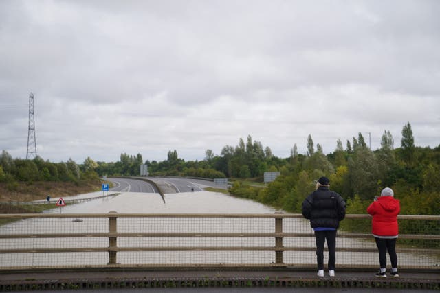People look at flood water on the A421 in Marston Moretaine, Bedfordshire (Joe Giddens/PA)