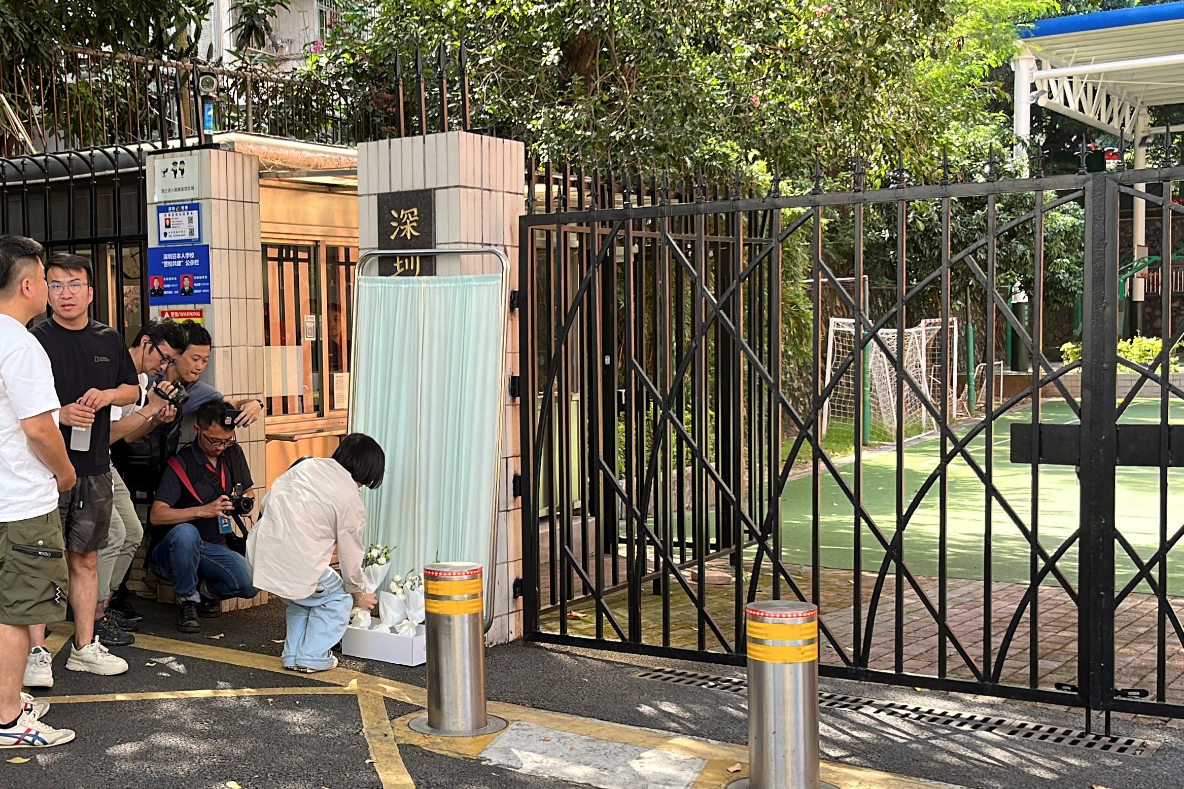 A woman lays a bouquet of flowers outside Shenzhen Japanese School in Shenzhen