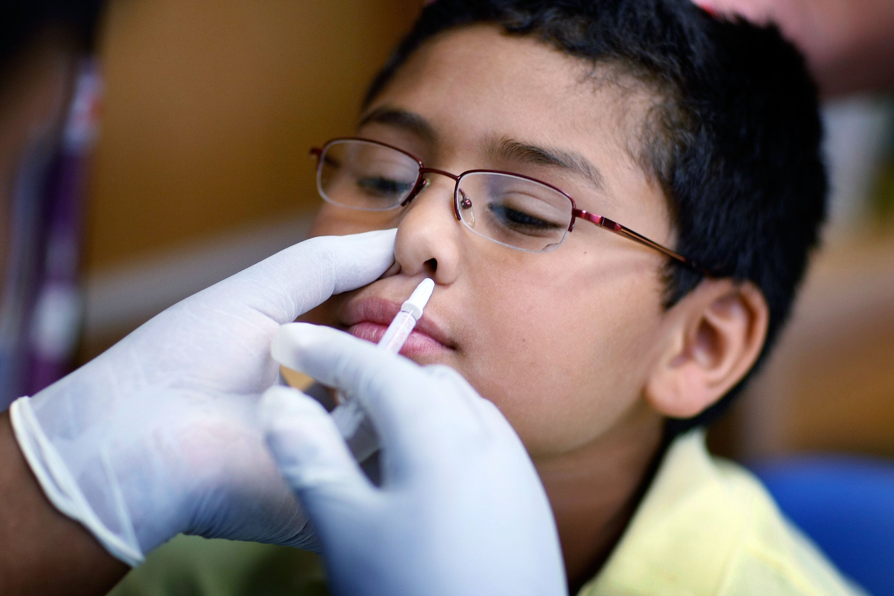 Chris Diaz, age 8, receives a H1N1 nasal flu spray vaccine from a nurse in Miami, Florida, in October 2009. The Centers for Disease Control and Prevention recommends that everyone six months and older receive an annual flu vaccine. Children are particularly susceptible to infection.