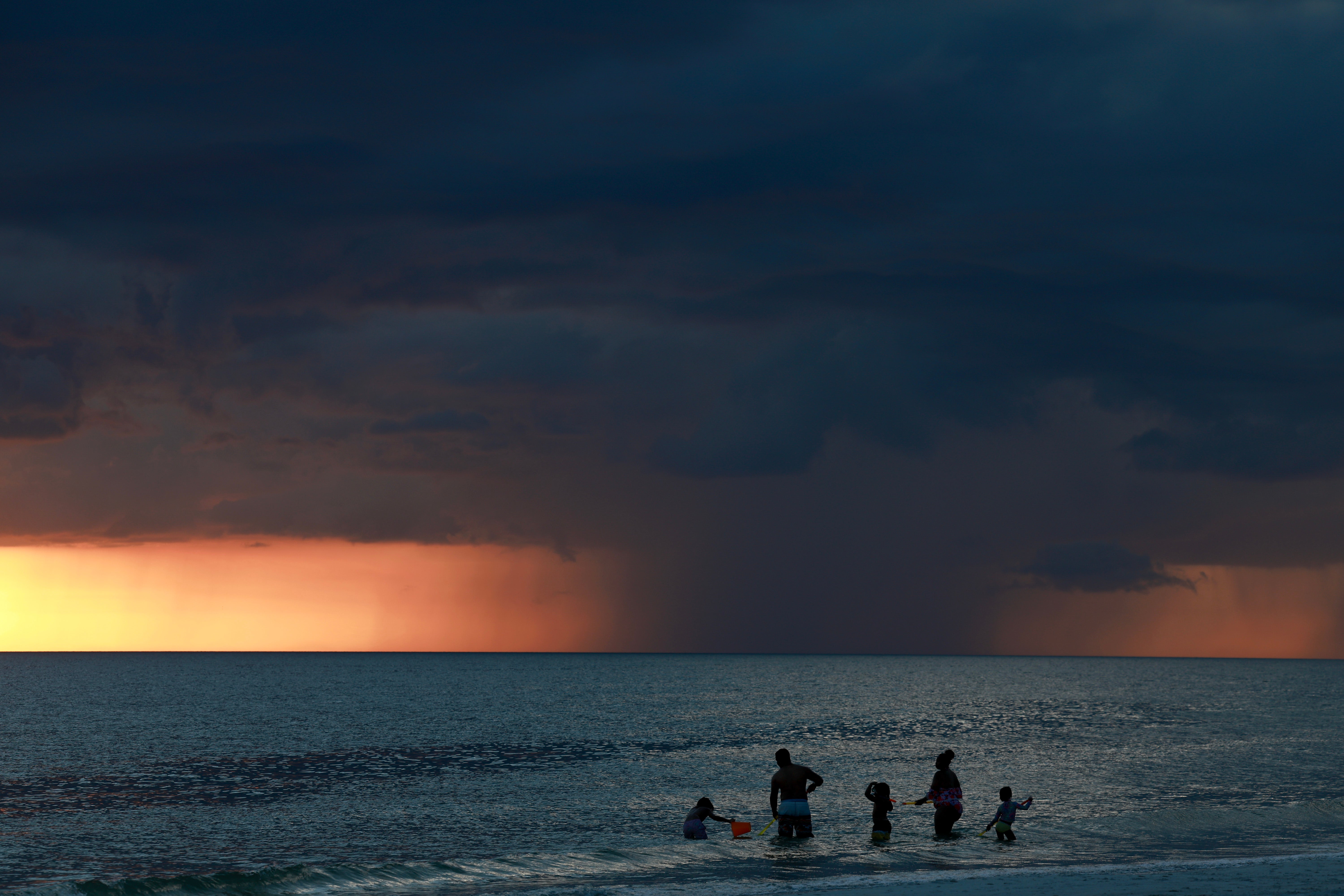 Storm clouds are visible on the horizon as the sun sets in St. Pete Beach, Florida on Tuesday